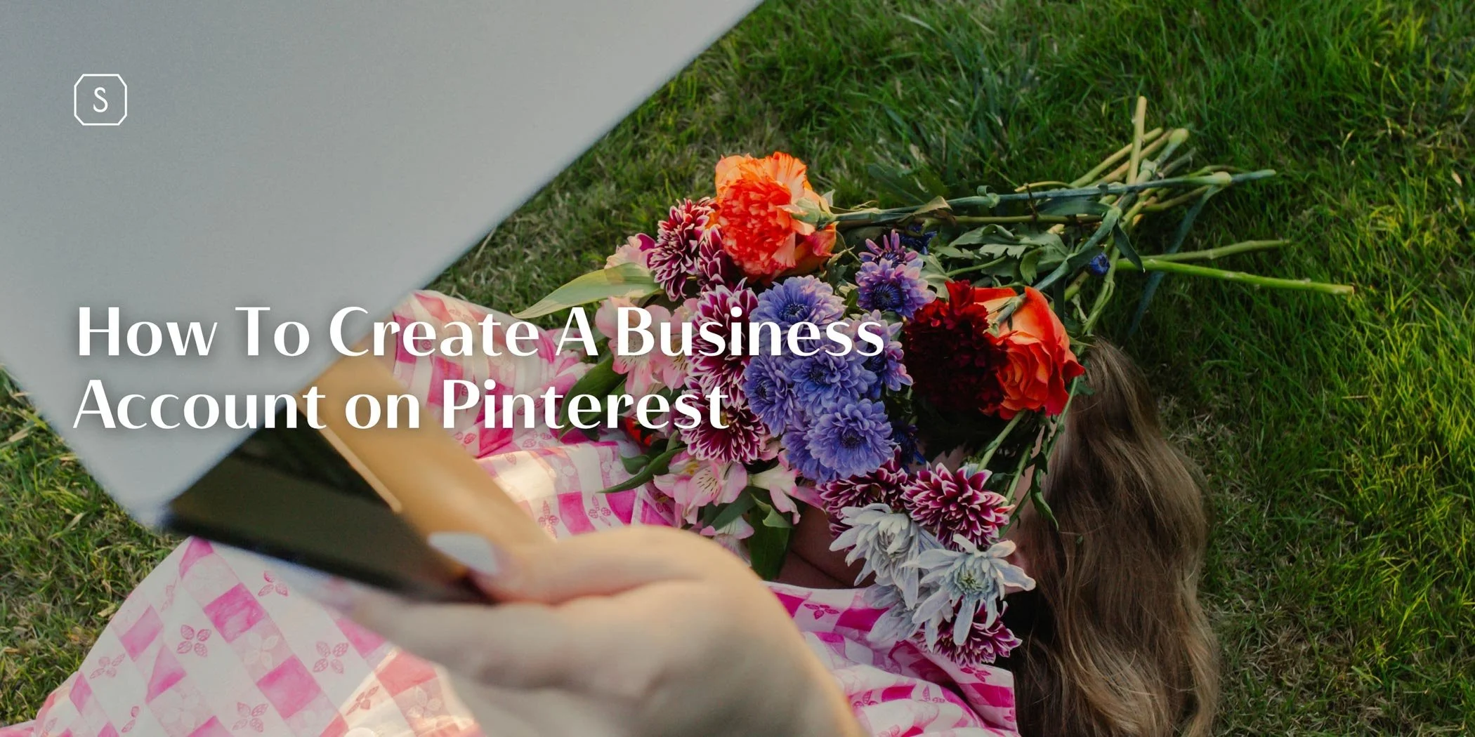 Woman using a laptop outdoors with text overlay about creating a business account on Pinterest
