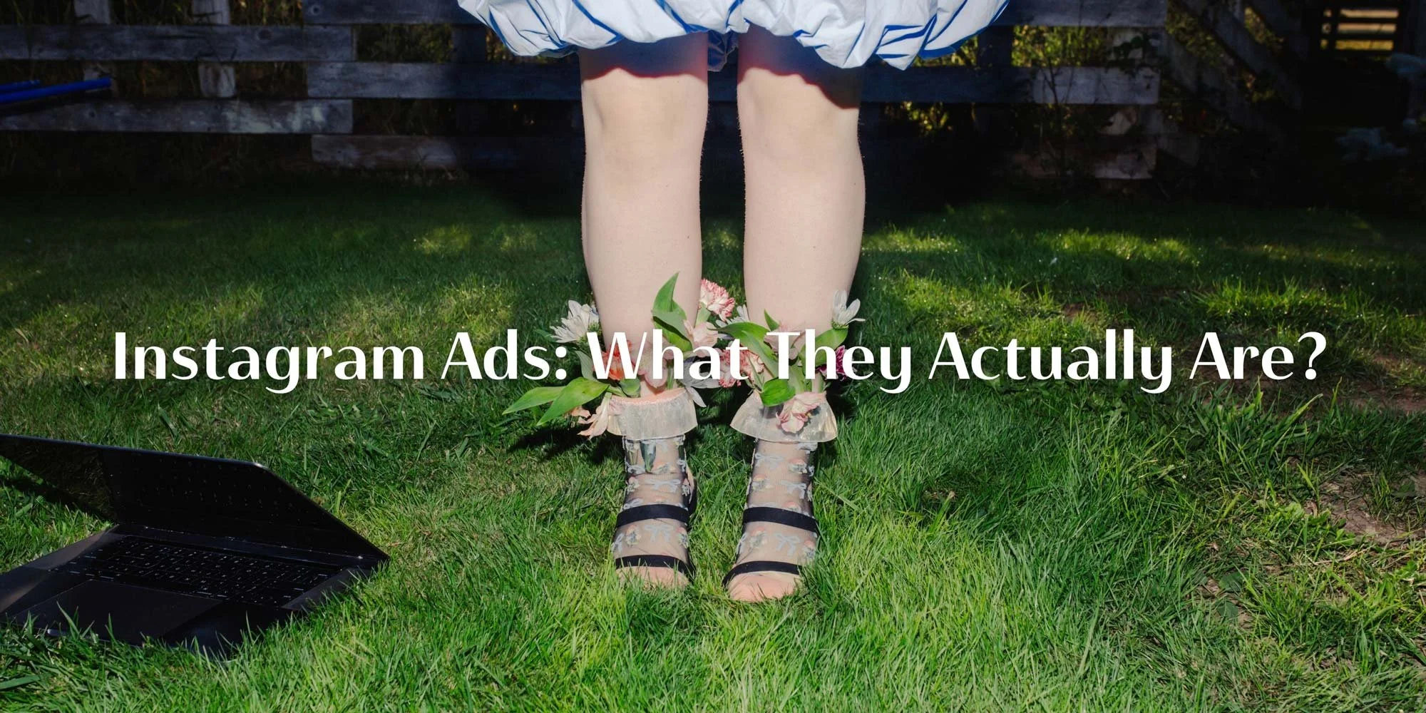 Person standing outdoors with laptop on grass, representing learning what Instagram ads are and how advertising on Instagram works