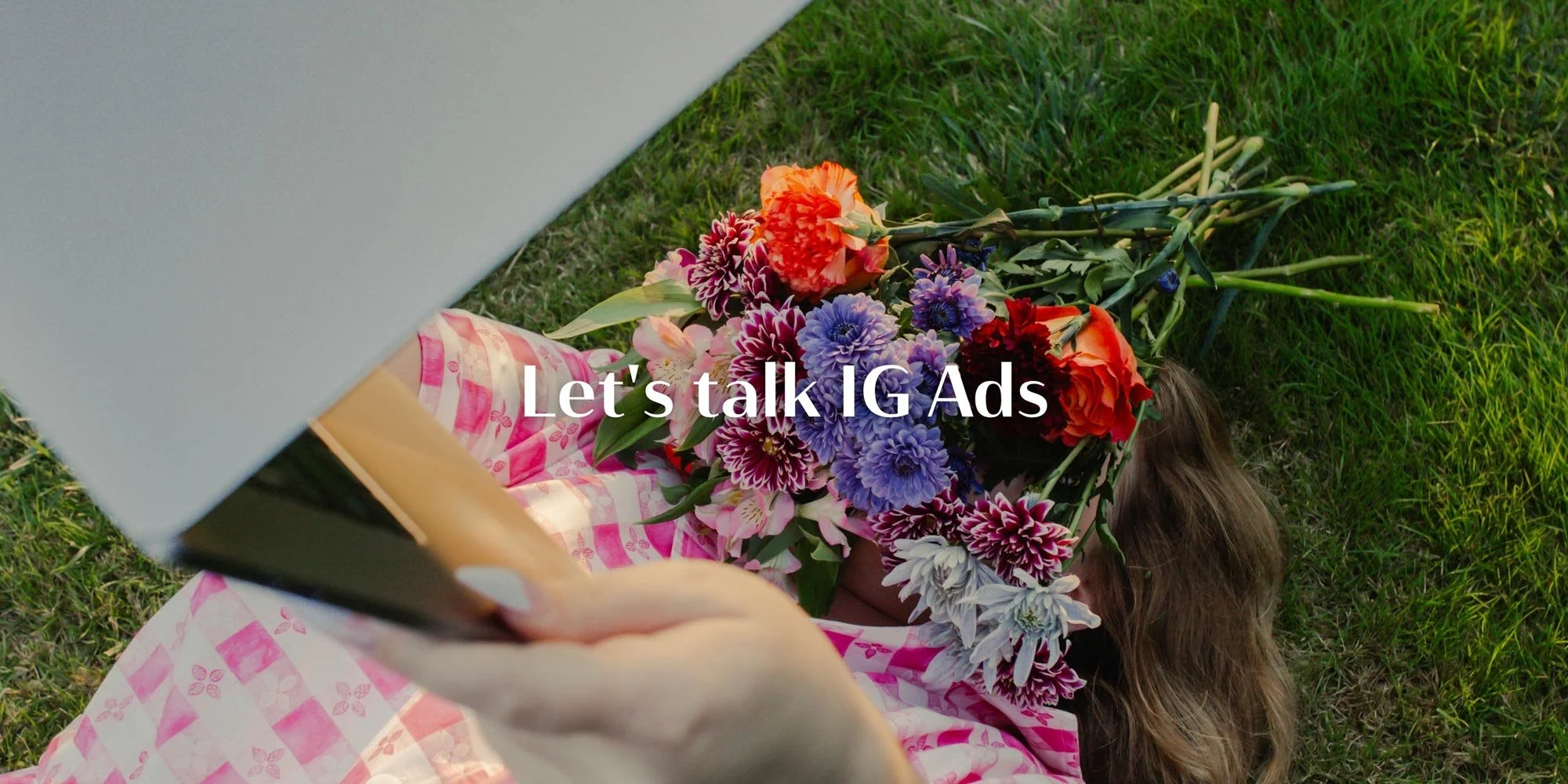 Person lying on grass with flowers and laptop, symbolizing planning and strategy for Instagram ads and digital marketing