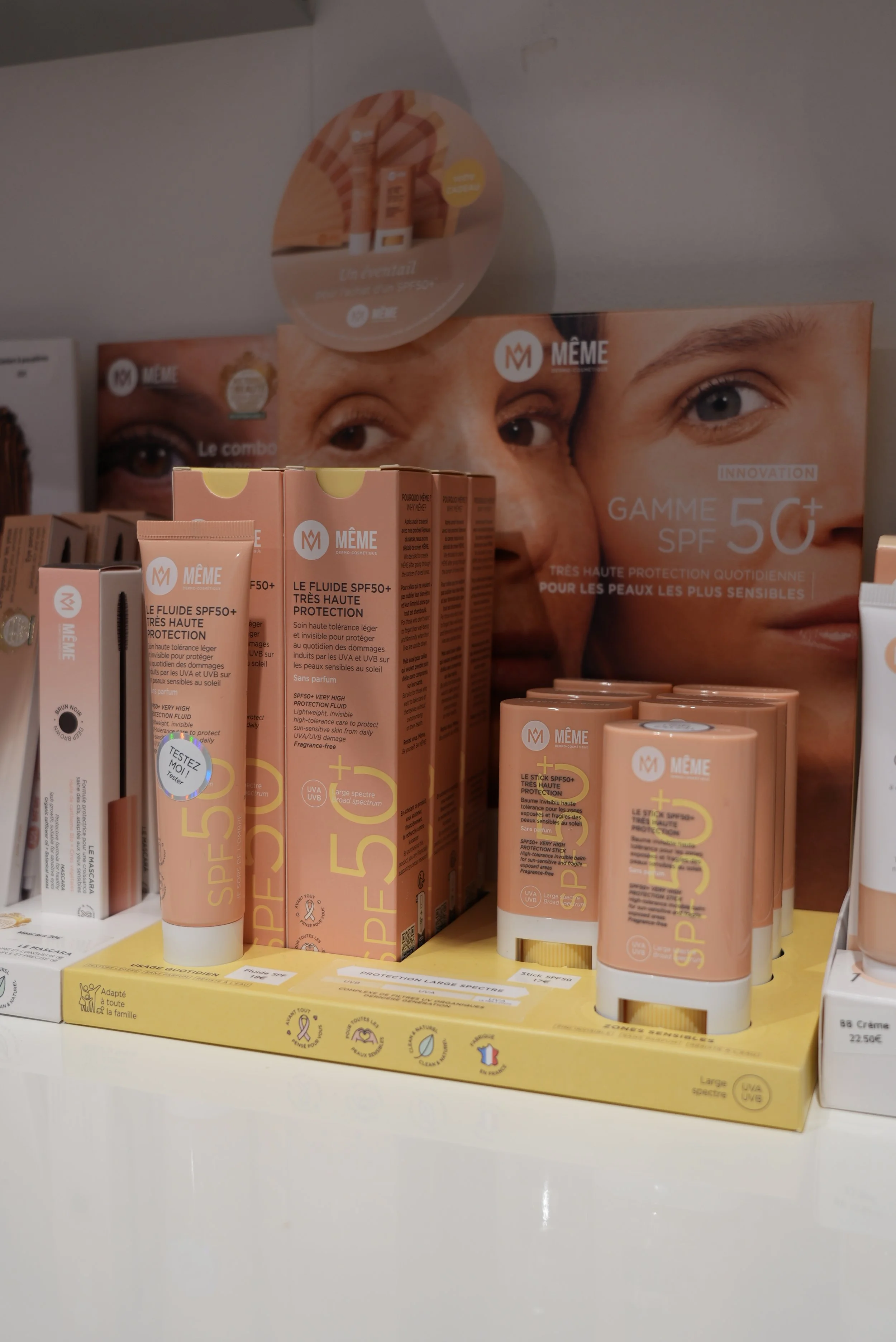 Produits solaires pour la protection UV SPF50+ de la marque MÉMÉ, en tubes et boîtes, exposés sur un rayon d'une pharmacie ou d'un magasin.