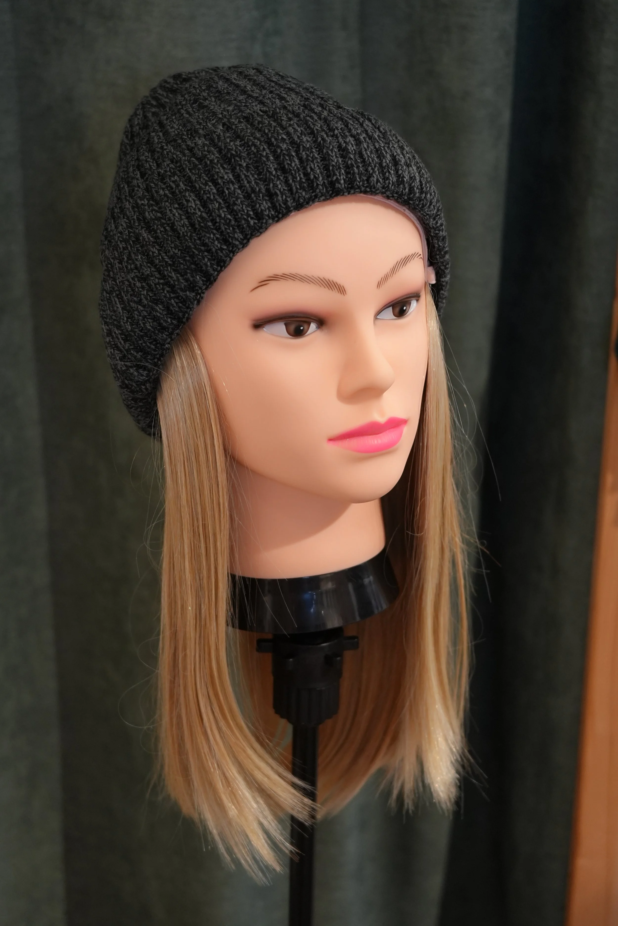 Mannequin tête avec longue chevelure blonde, portant un bonnet en laine gris foncé, sans autres accessoires ou vêtements visibles.