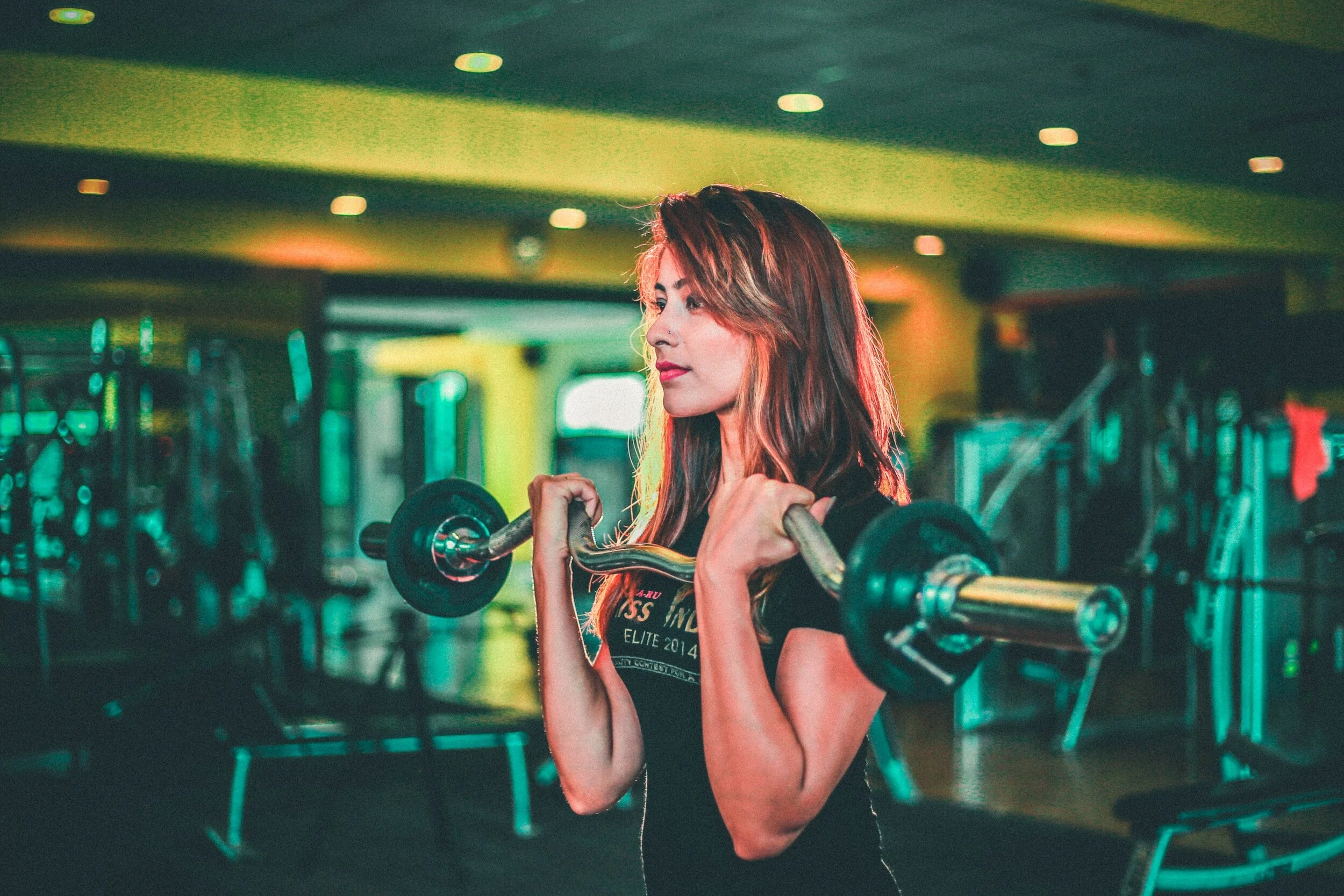 Image of young woman in gym lifting weights