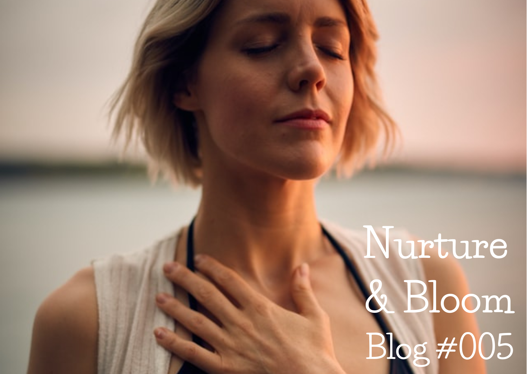 Image of woman meditating with her hand on her chest and her eyes closed. She has a slight smile on her face and she appears peaceful.