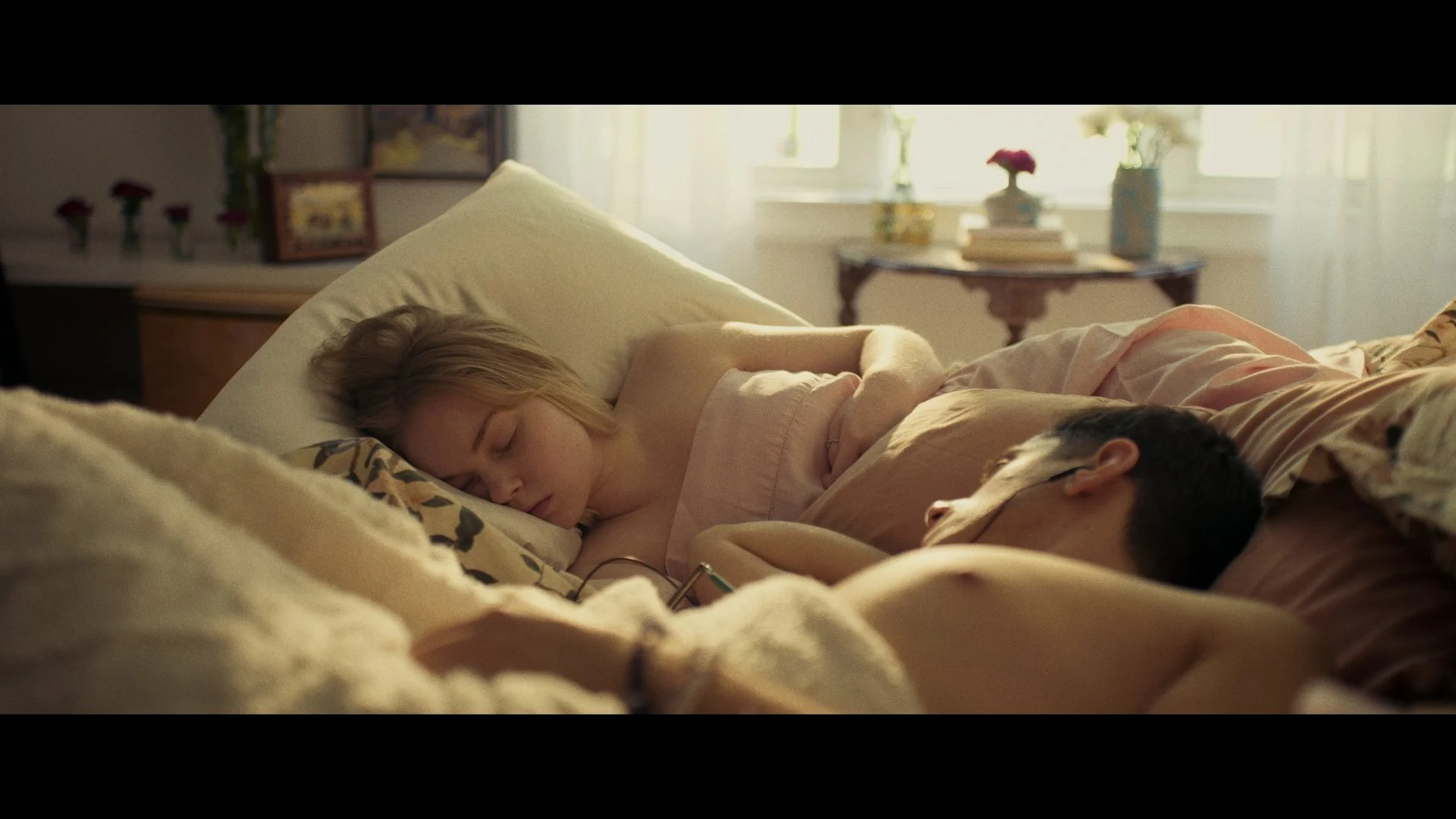A young woman and a man sleeping together in bed.