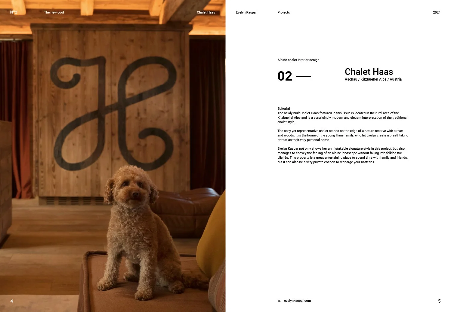 A small curly-haired dog sitting on a brown sofa in a rustic wooden room with a large wood-paneled wall that has a stylized black geometric shape painted on it. There are brown curtains and a leather armchair visible in the background.