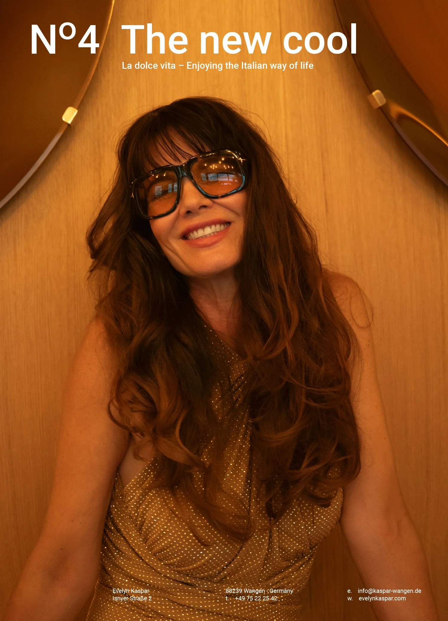 A smiling woman with long brown hair, wearing large sunglasses and a gold dress, sitting against a wooden wall with the text 'Nº 4 The new cool' at the top and additional smaller text promoting an Italian lifestyle.