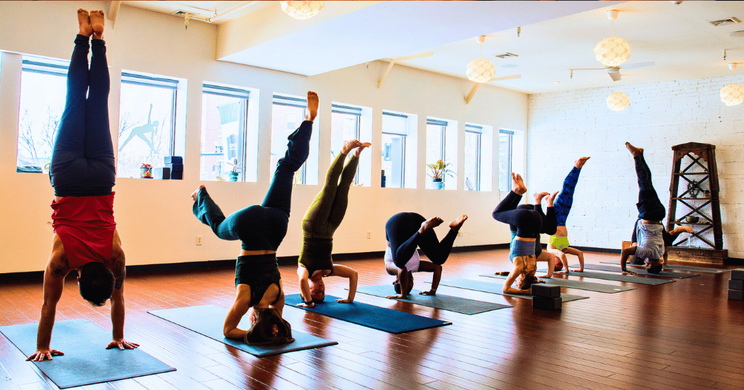 Group of people doing handstand yoga poses at Boston Yoga Union in Coolidge Corner
