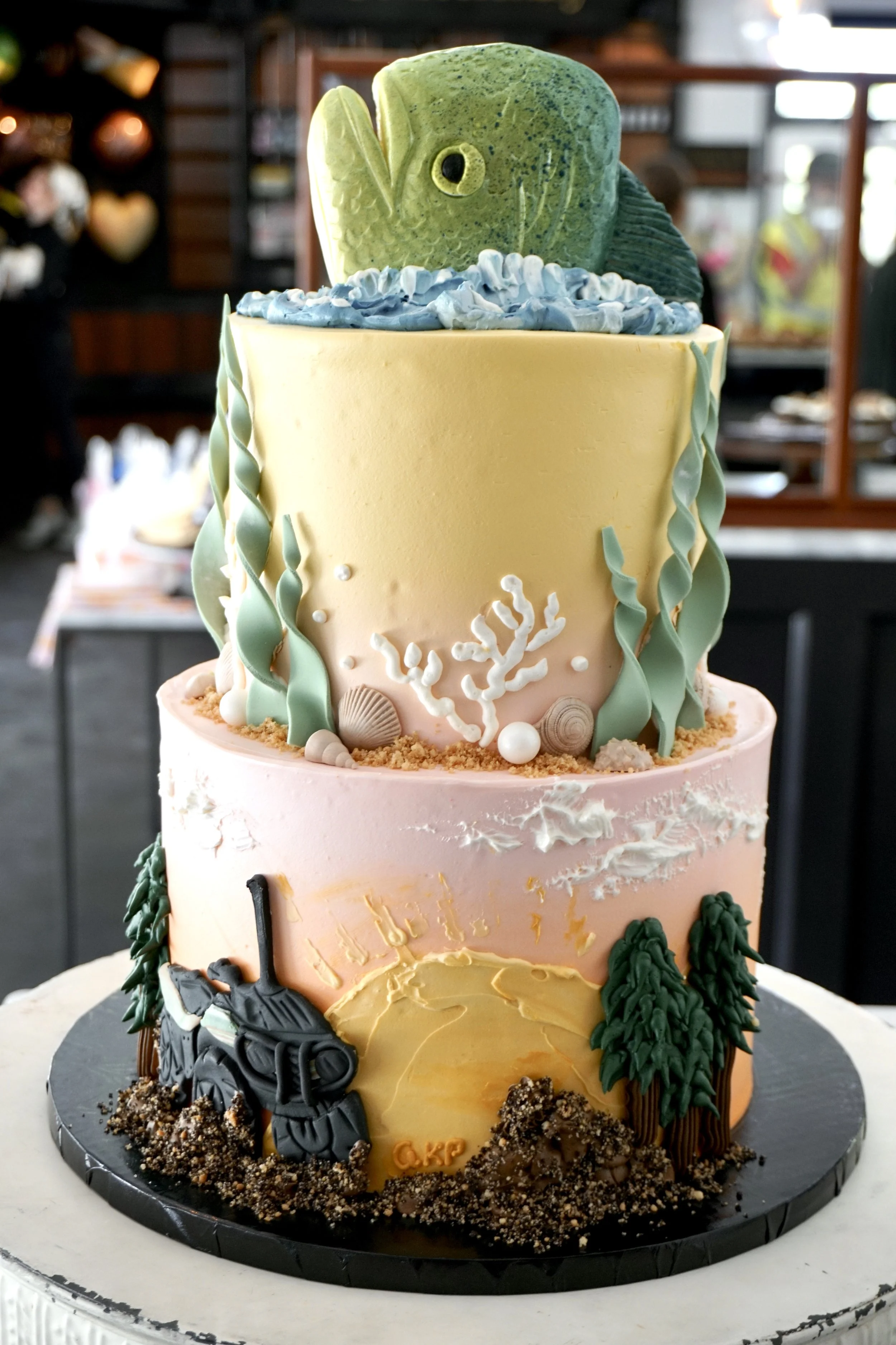 Two tier cake, ombre sunset buttercream, fish on top.JPG