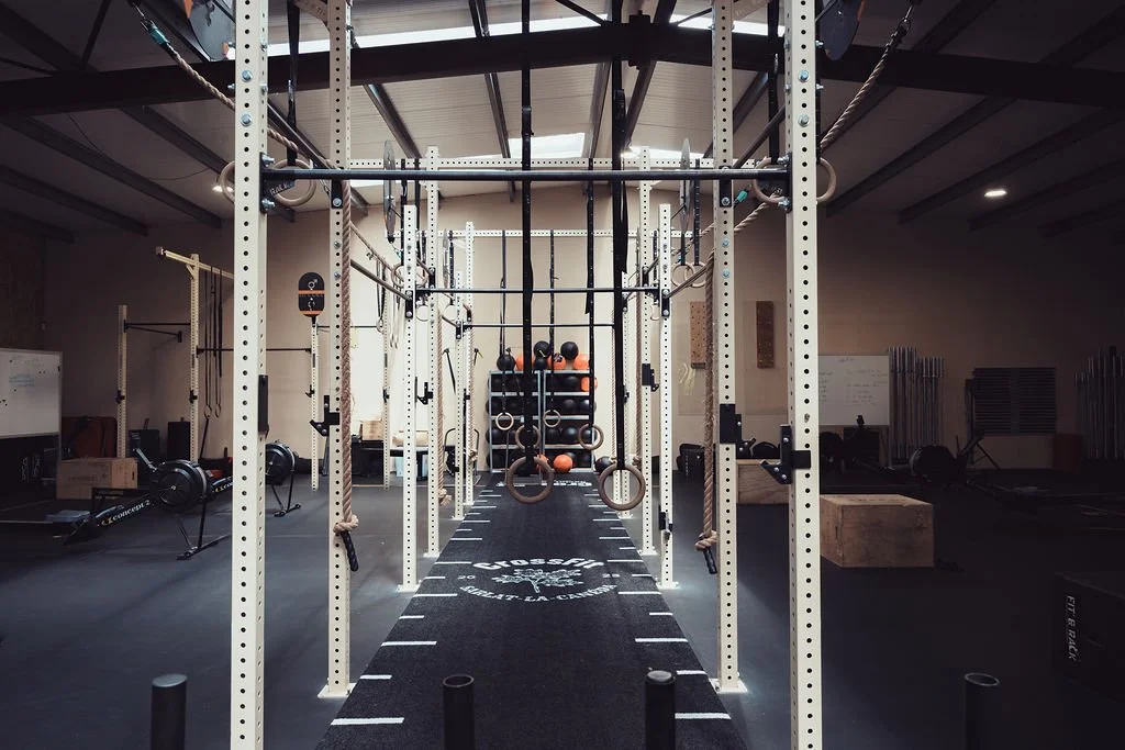 Salle de sport avec structures de CrossFit, rings, kettlebells et matériel d'entraînement connecté