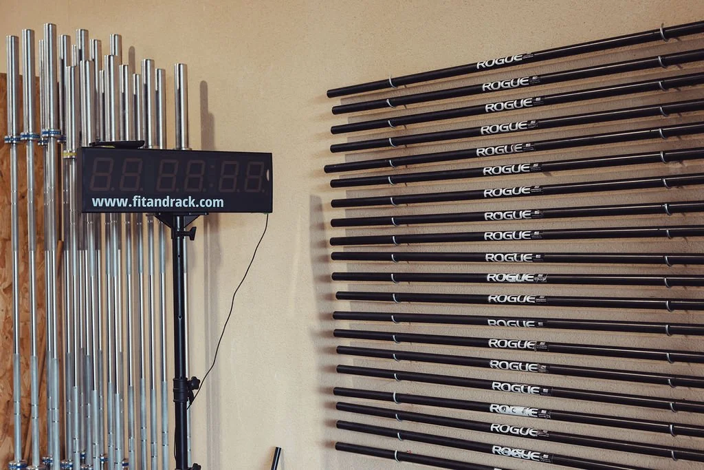 Barres de levage en PVC pour l'échauffement pour exercices de musculation avec un tableau numérique à côté, dans une salle de sport.