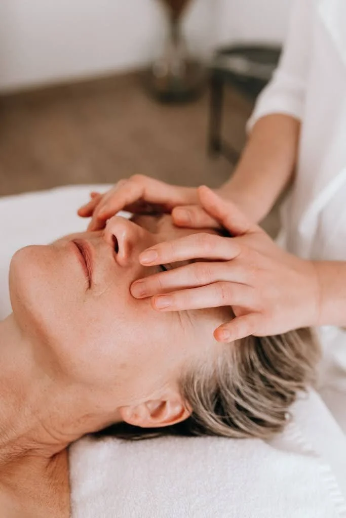 Personne recevant un massage du visage dans un spa ou cabinet de massage.