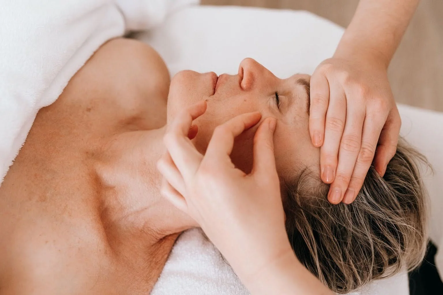 Une personne reçoit un massage du visage dans un cadre de spa ou de soins de beauté.