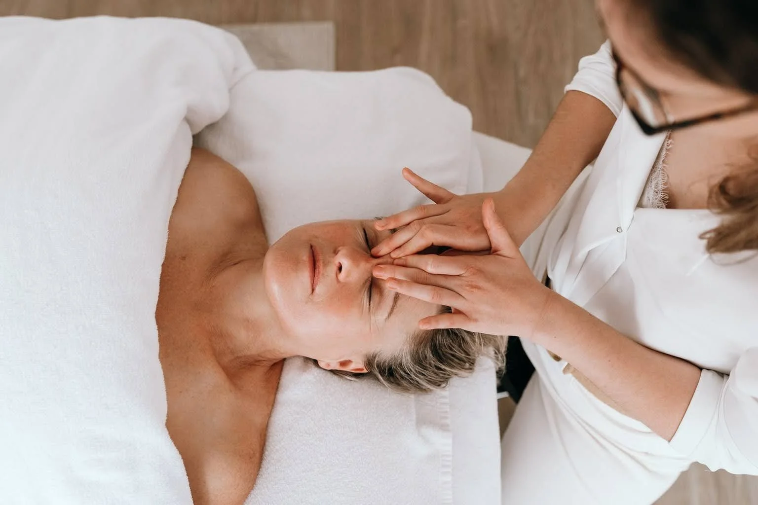 Une femme reçoit un massage facial dans un spa ou un centre de bien-être.