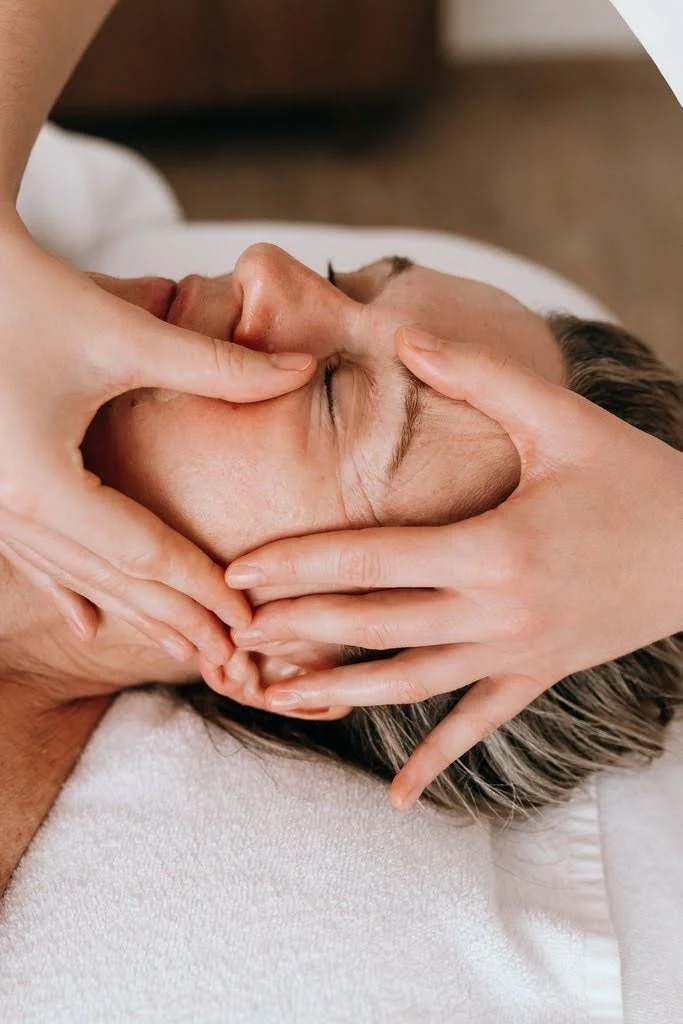 Une personne reçoit un massage du visage dans une salle de spa ou de massage.