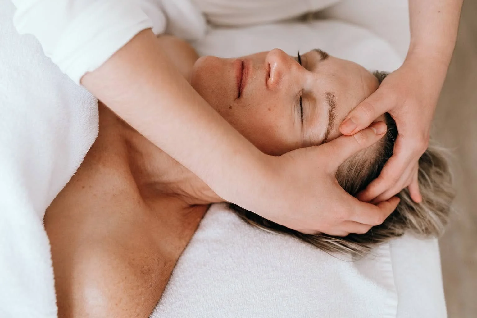 Une femme reçoit un massage de la tête par un thérapeute dans une salle de spa.