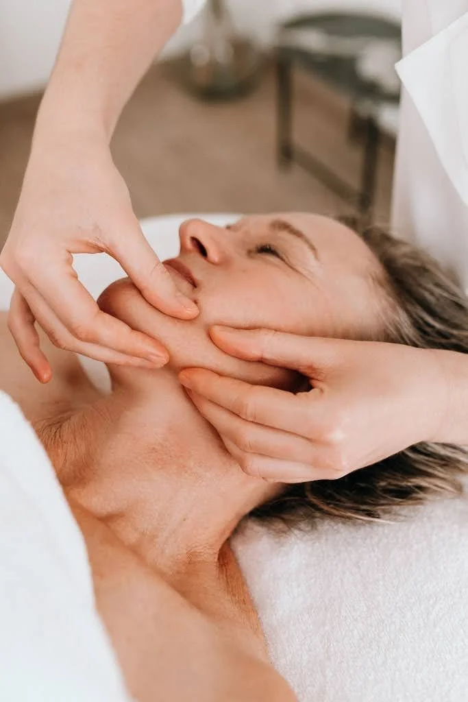 Une personne reçoit un massage du visage dans un spa ou un centre de soins.