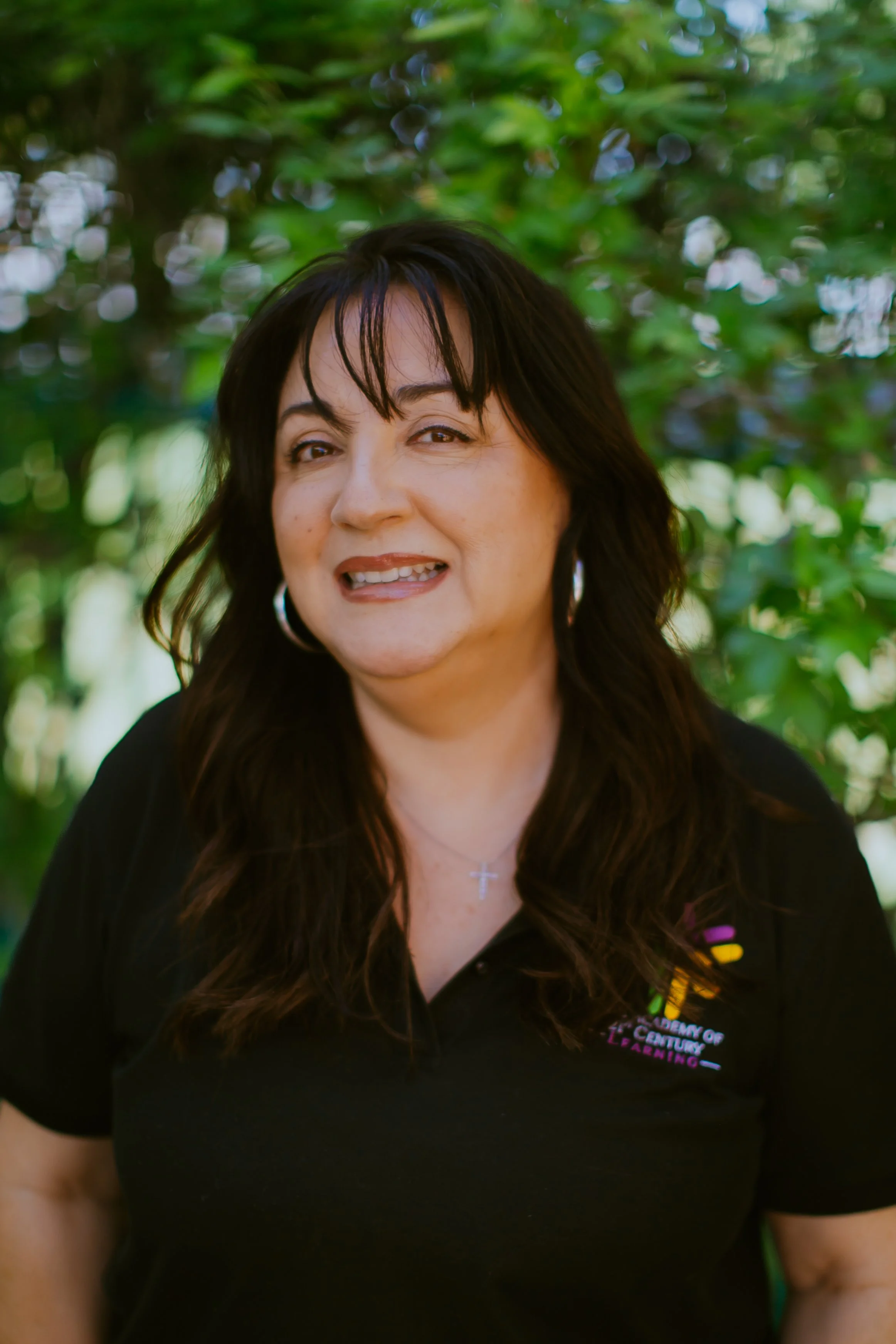 Smiling woman with dark hair wearing a floral blouse.
