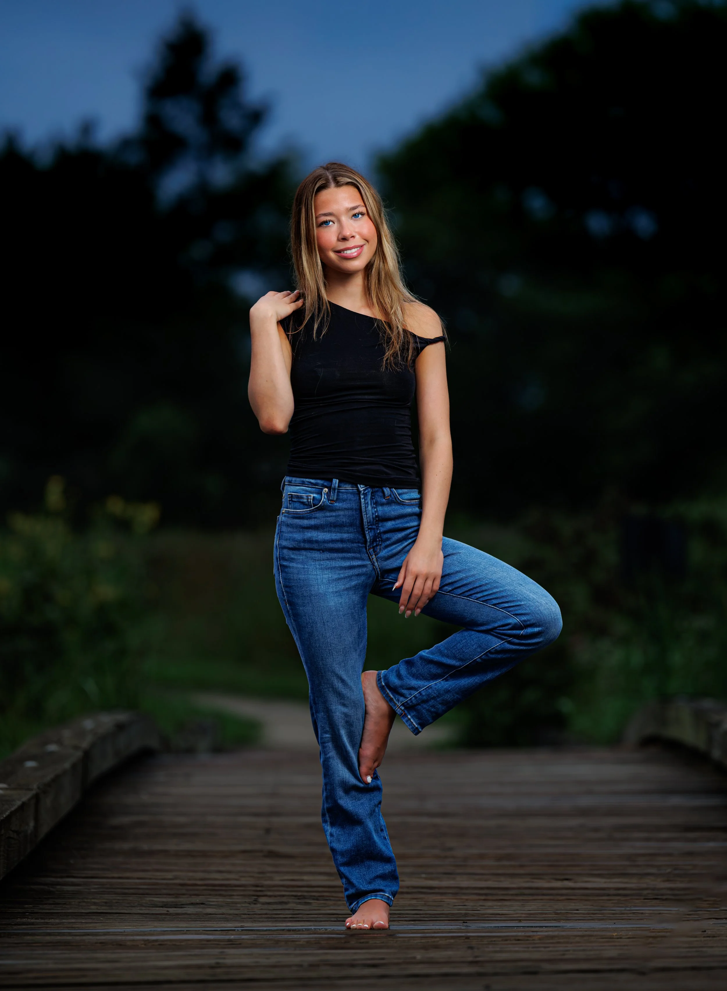 High school senior, standing on one leg in jeans and black tank in gallery park glenview 