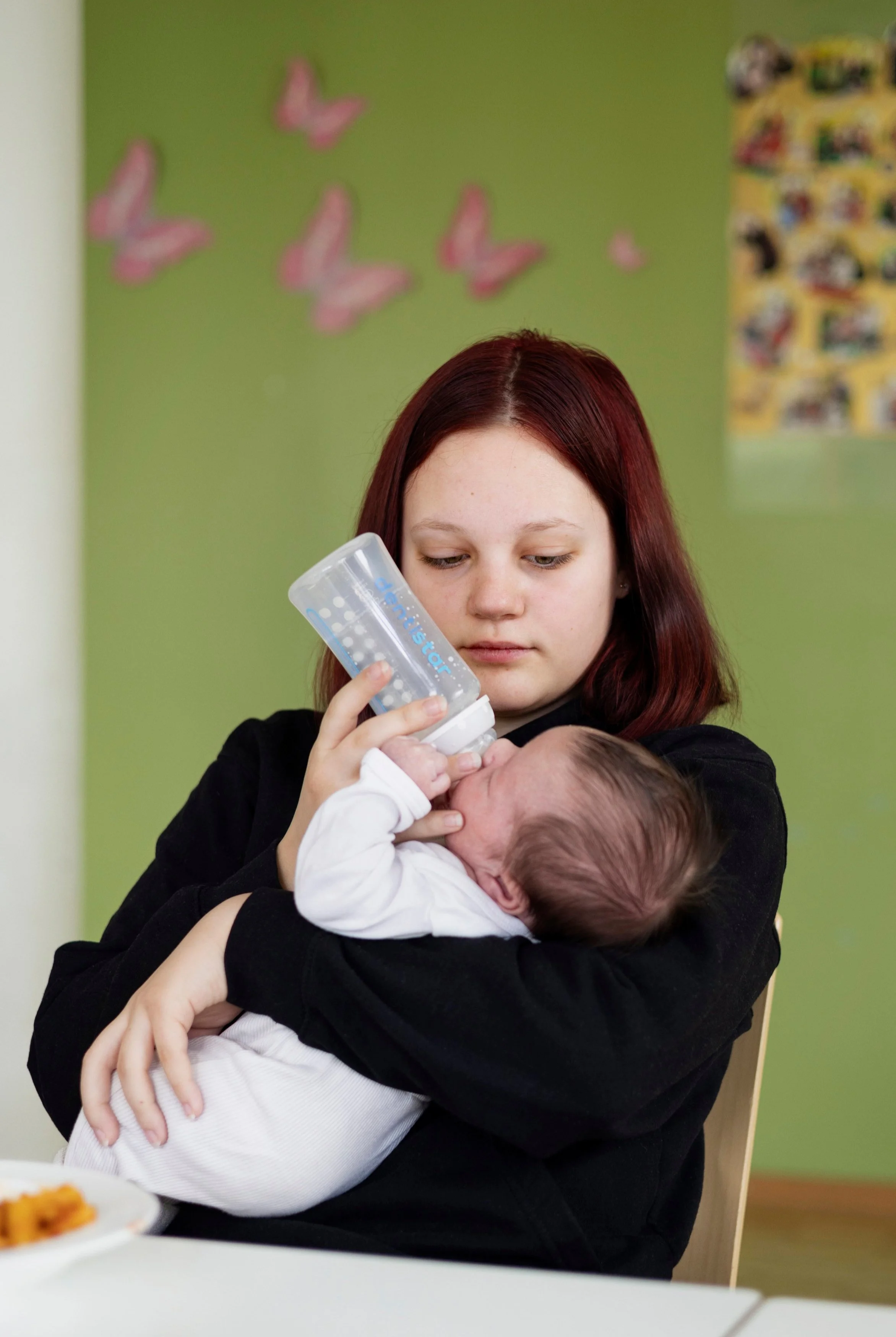 Junge Mutter mit einem Baby auf dem Arm das gerade aus deiner Babyflasche trinkt: Kuratierte Unternehmensdokumentation für die Stiftung Waisenhaus Frankfurt