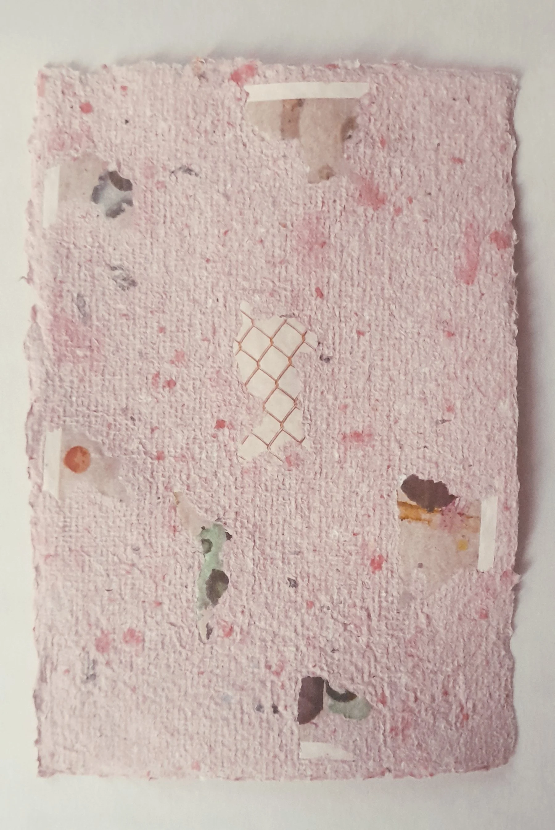 EIn rosanes handgeschöpftes Papier mit eingearbeiteten Papierdetails und abstrakten Formen