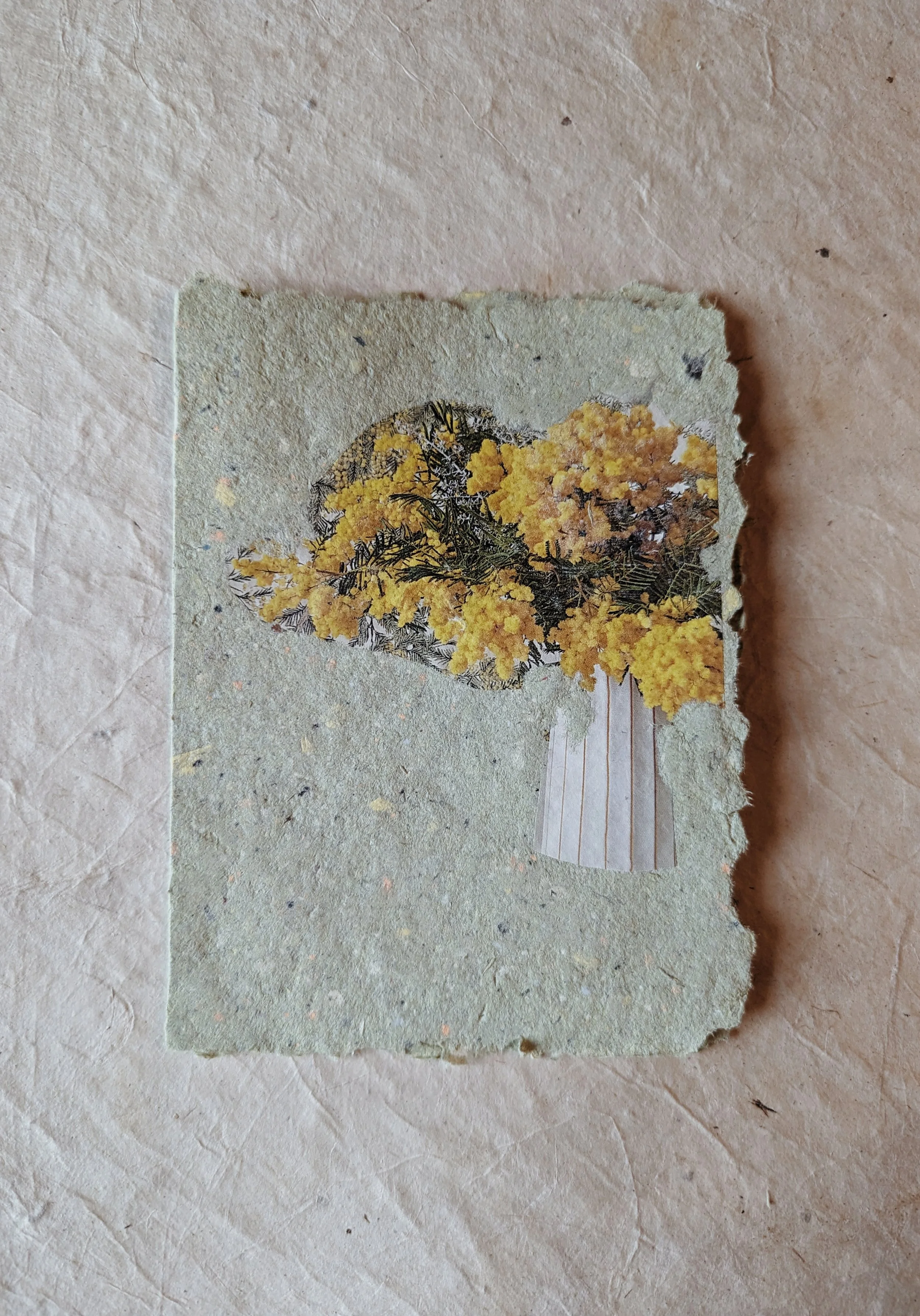 Ein Stück zerfleddertes Papier mit einer Abbildung eines gelben Blumenstraußes auf grauem Hintergrund.