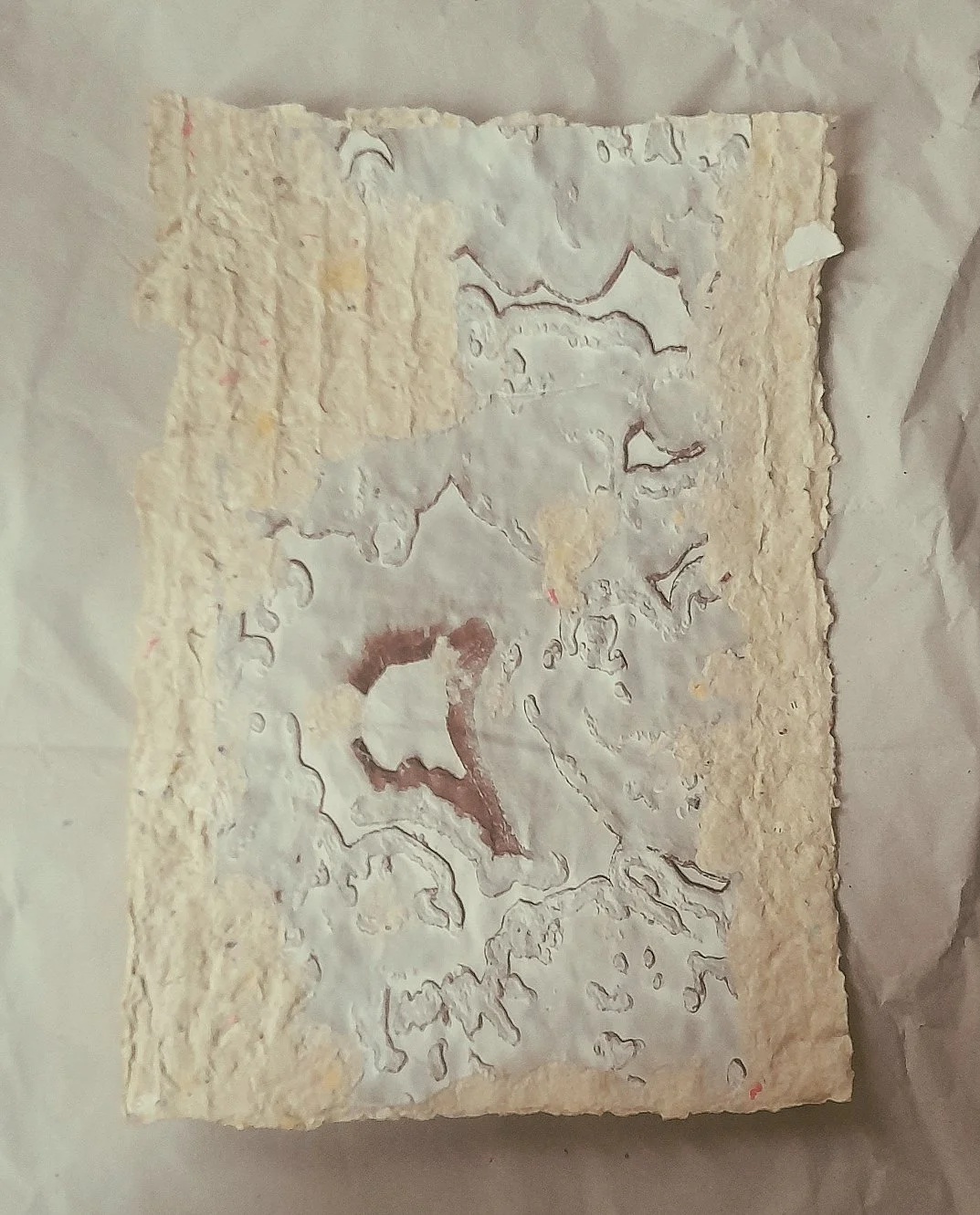 Ein Stück mit Marmorierung, wahrscheinlich ein Kuchen oder eine Torte, mit weißer Glasur und Rissen, auf Pergamentpapier