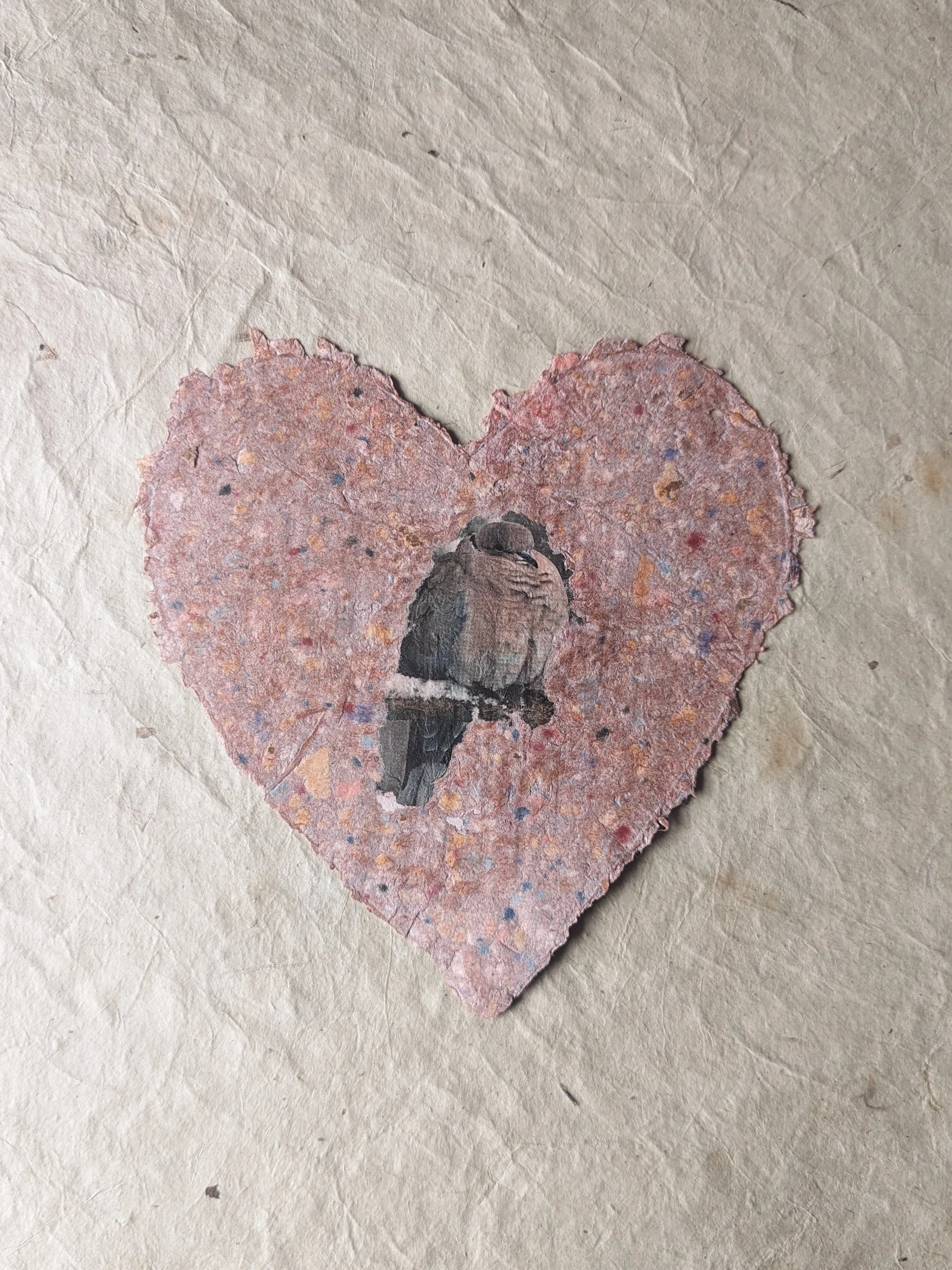 Ein Herz aus geschöpftem Papier mit einem Vogel in der Mitte