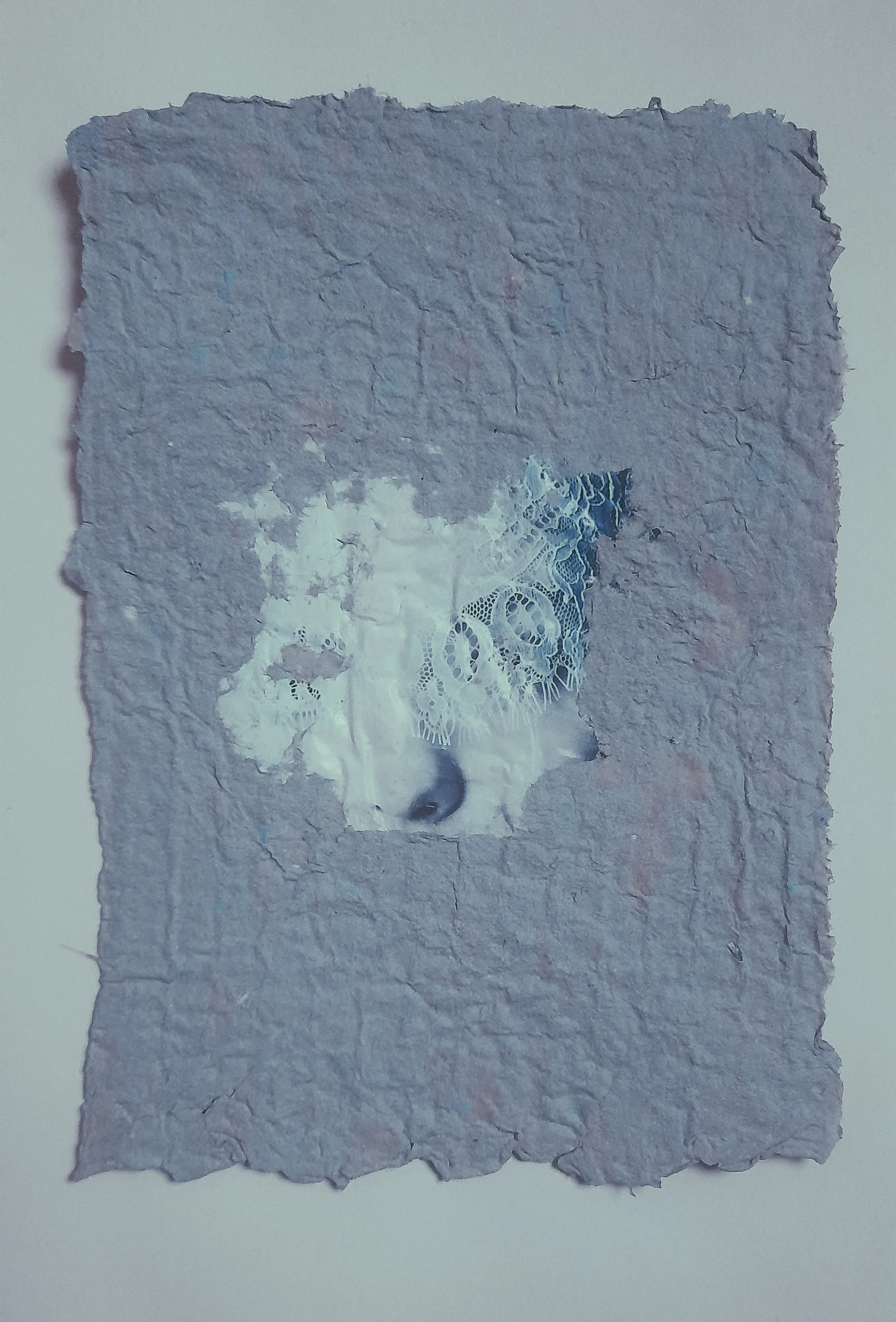 Ein Kunstwerk aus zerknittertem Papier mit einem Gesicht, das teilweise sichtbar ist, durch ein Loch in der Mitte des Papiers, mit einem offenen Mund und einer Nase.