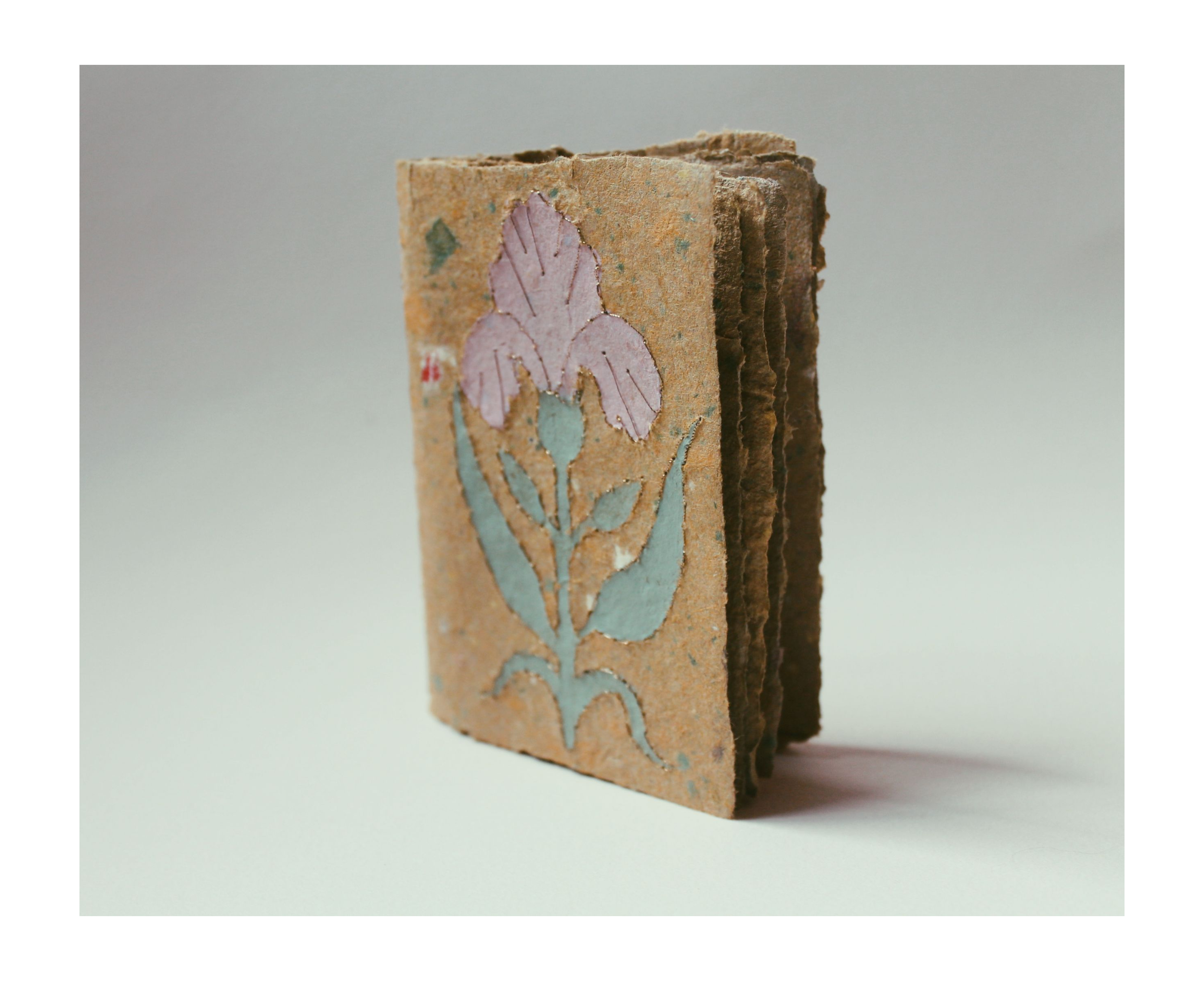 Ein alter, bemalter Ziegelstein mit floralem Muster, das eine Blume mit Blättern darstellt.