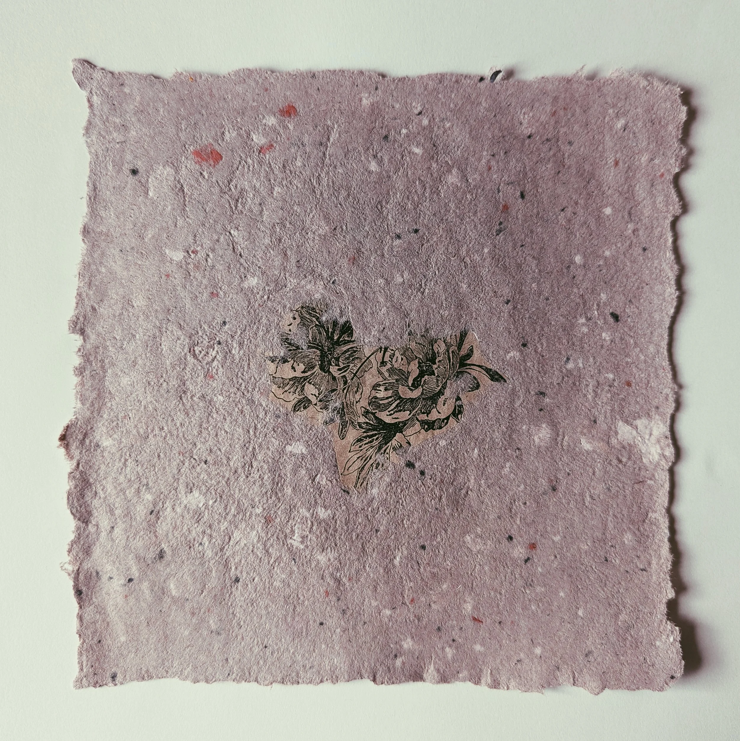 Aquarellpapier mit floralem Druck in der Mitte auf cremefarbenem Hintergrund.