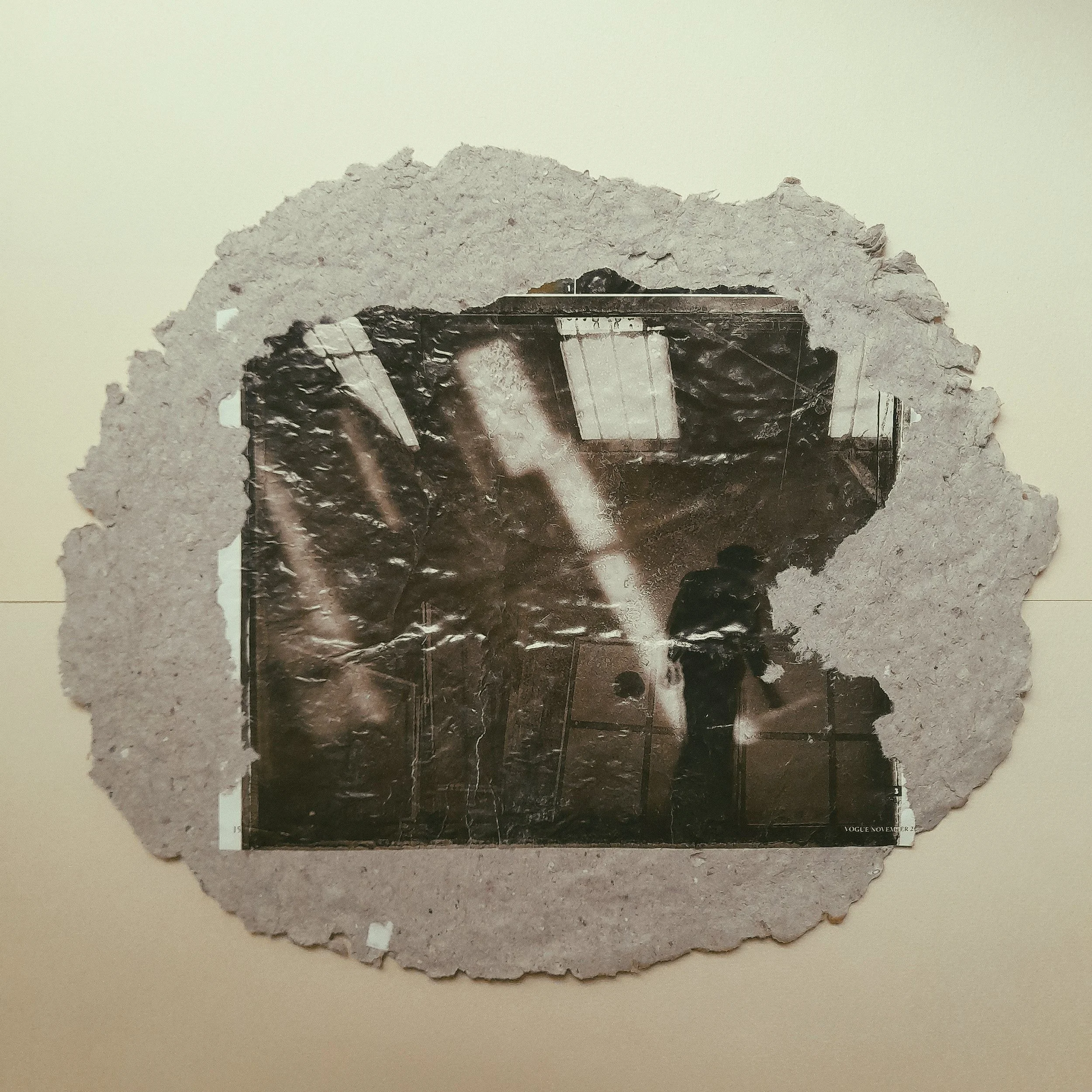 Schwarz-weiß-Foto eines Menschen, der in einem Raum steht, sichtbar durch eine löchrige Pappe oder einen Tunnel, mit Lichtstrahlen und einer Decke mit Beleuchtung im Hintergrund.