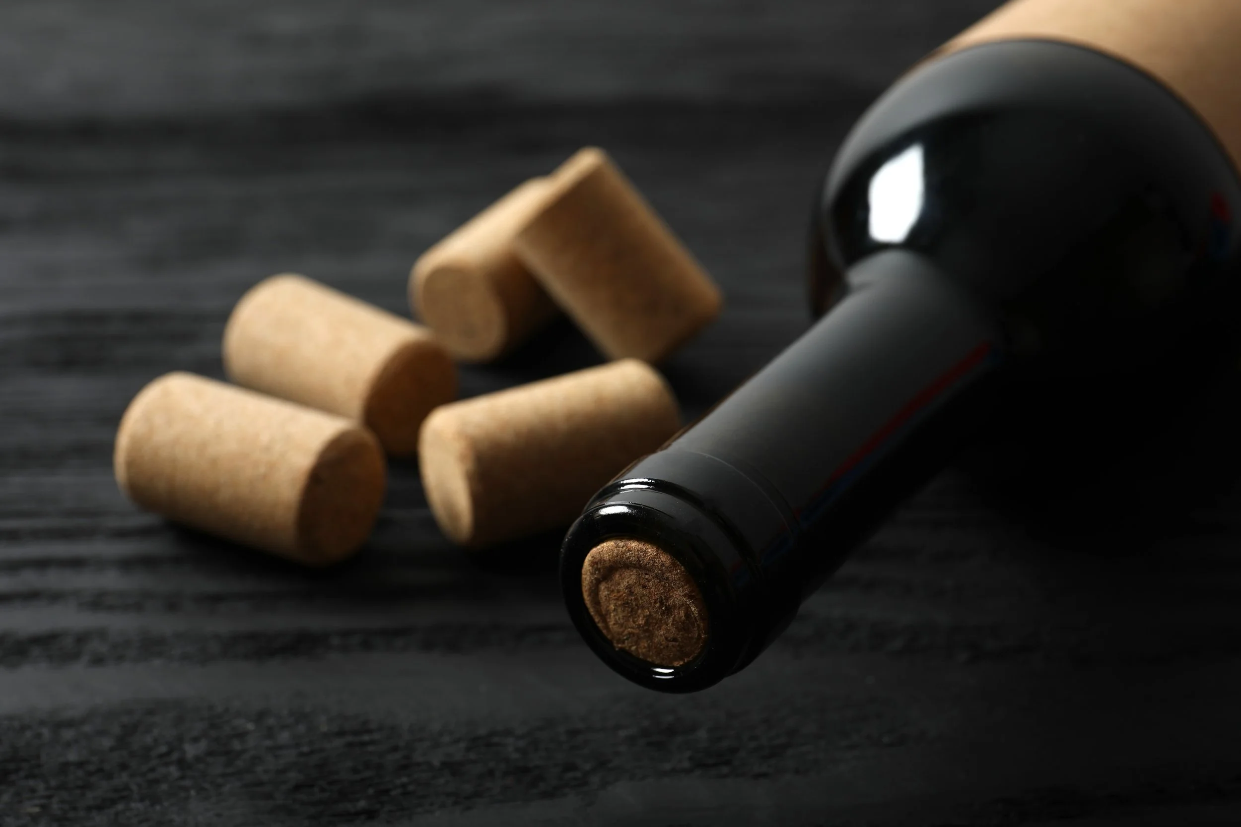 A wine bottle lying on its side next to natural corks, two of the packaging materials wineries report under EPR