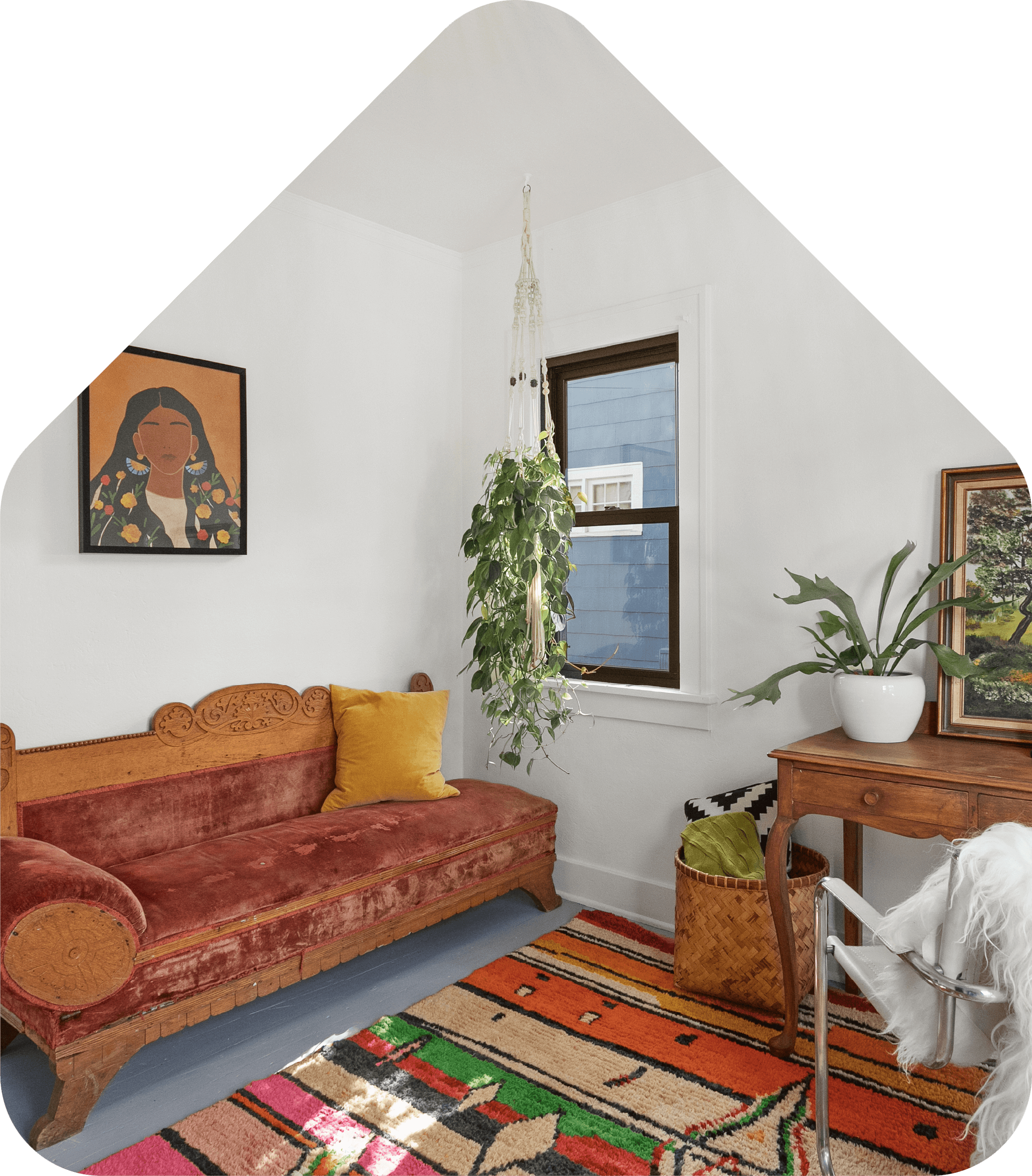 A cozy living room with a vintage wooden sofa, a colorful patterned rug, a wooden side table with a potted plant, and wall art, illuminated by natural light from a window.