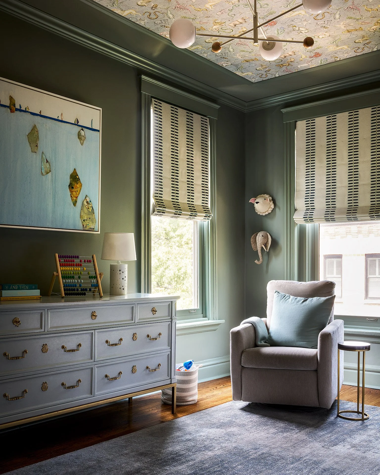 A nursery with earth tone and wallpaper on the ceiling