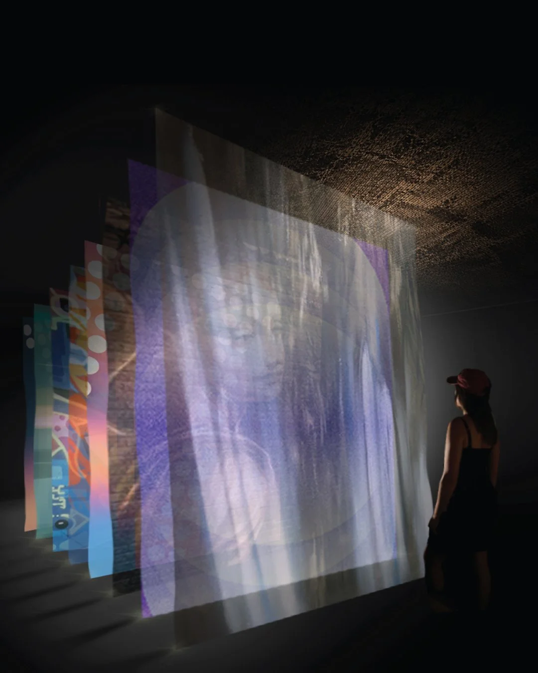 an etherial art installation of layers of painting translucent fabric suspended from a tall ceiling and lit in a dark room revealing the artworks. 