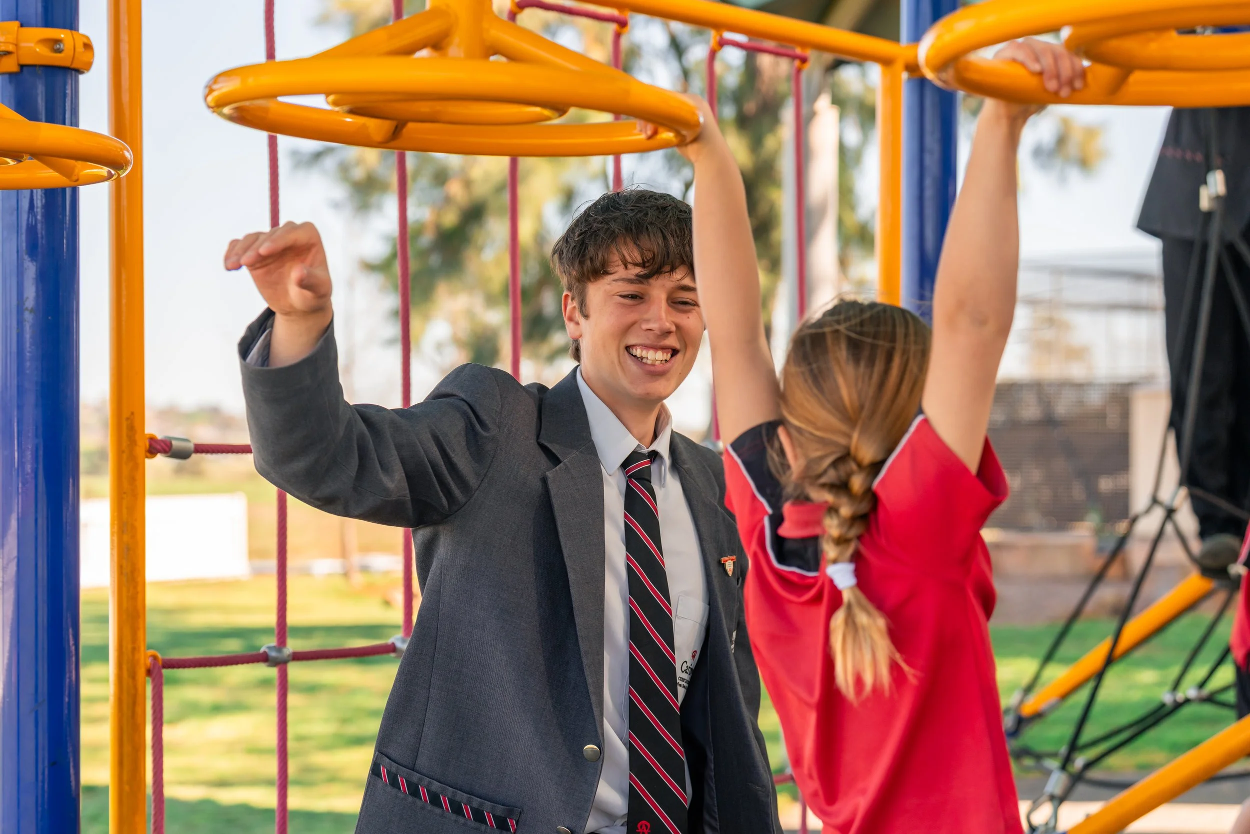 A Senior School student playing with a Junior School student on the outdoor play equipment at Carinya Christian School, Tamworth.