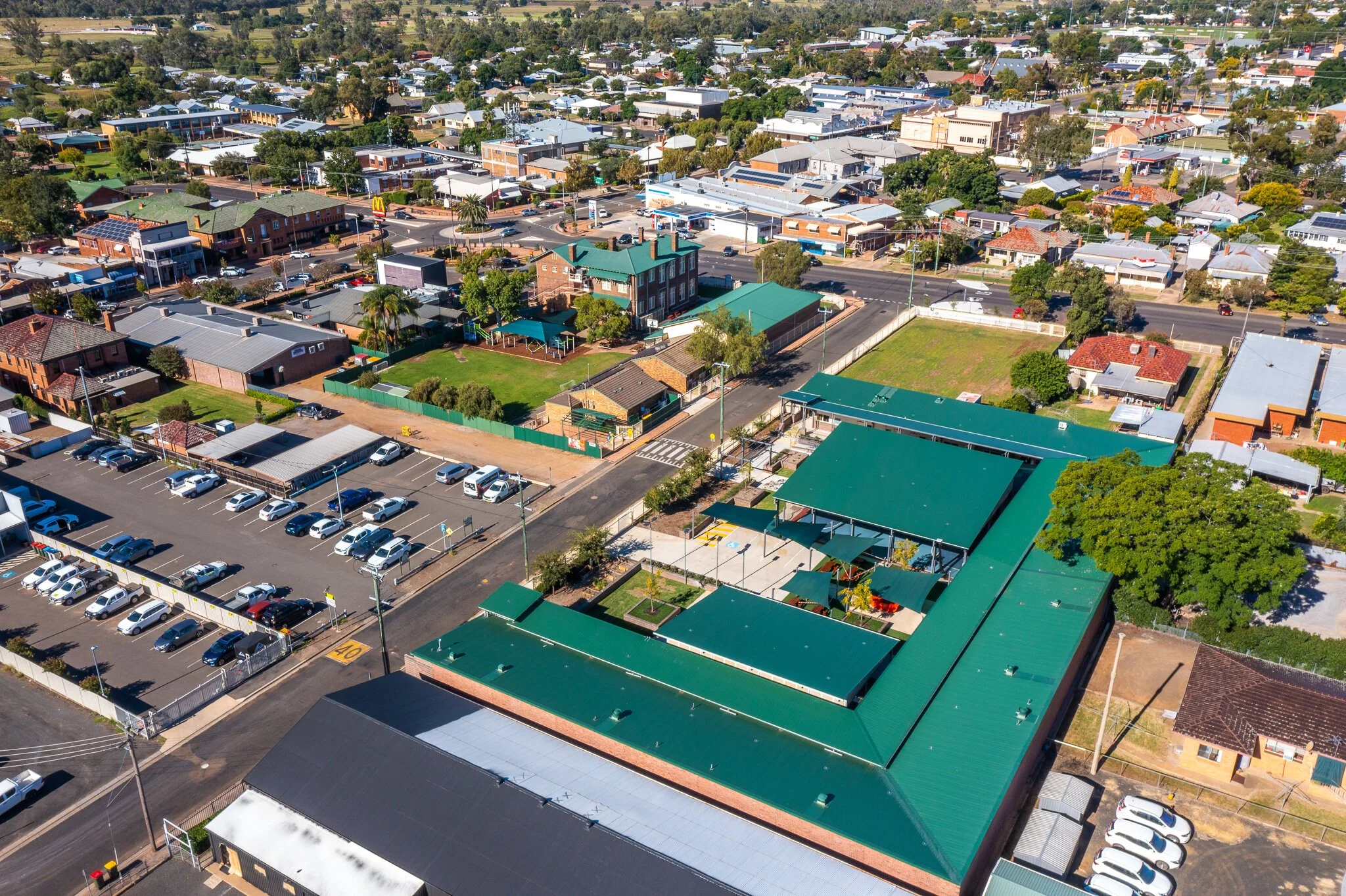 Aerial view of a small town with a mix of residential and commercial buildings, parking lots, and green spaces.