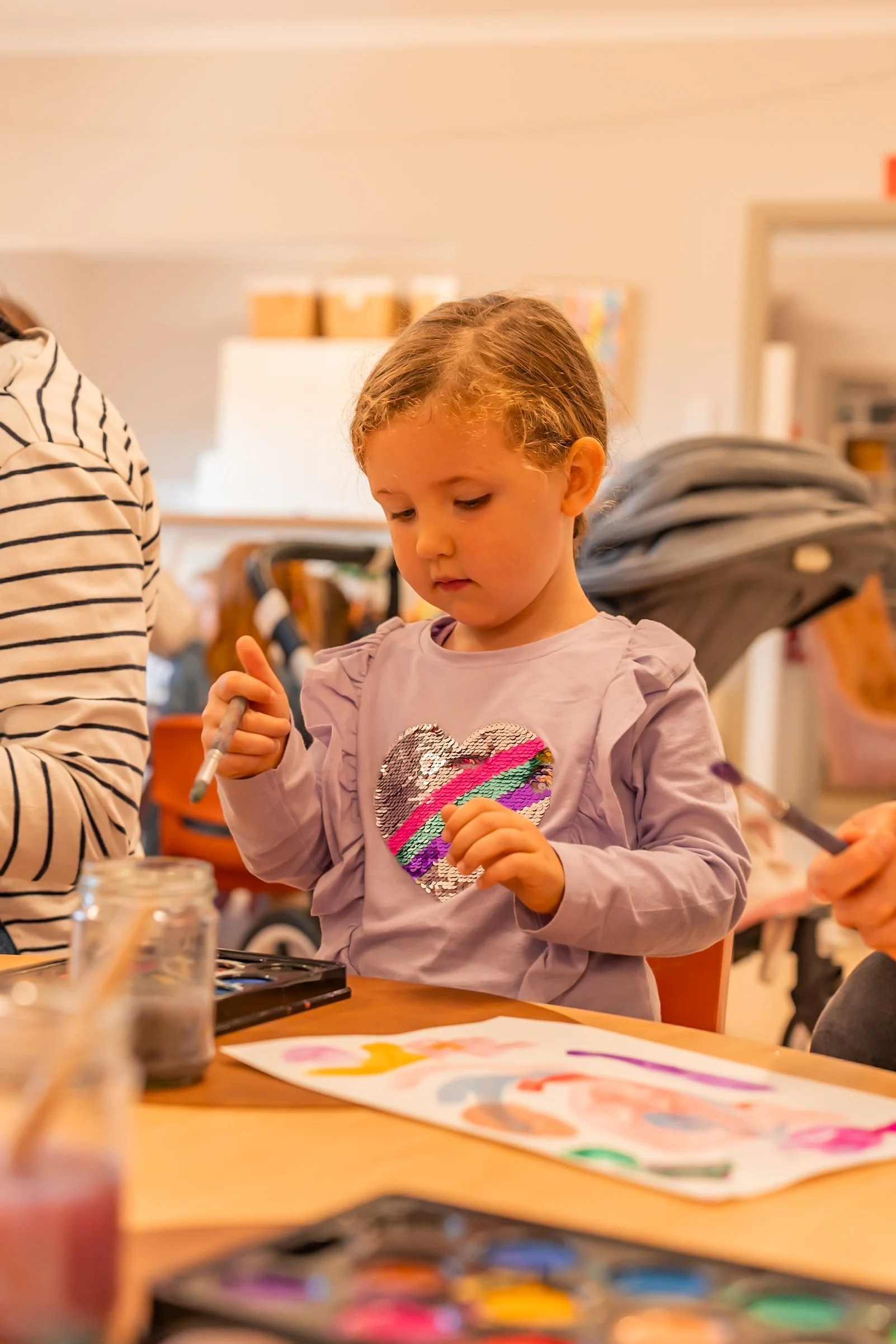 Gumnuts student painting with watercolour paints at a table,  at Lilly Pilly Preps 3 Year Old Program in a classroom at Carinya Christian School, Tamworth