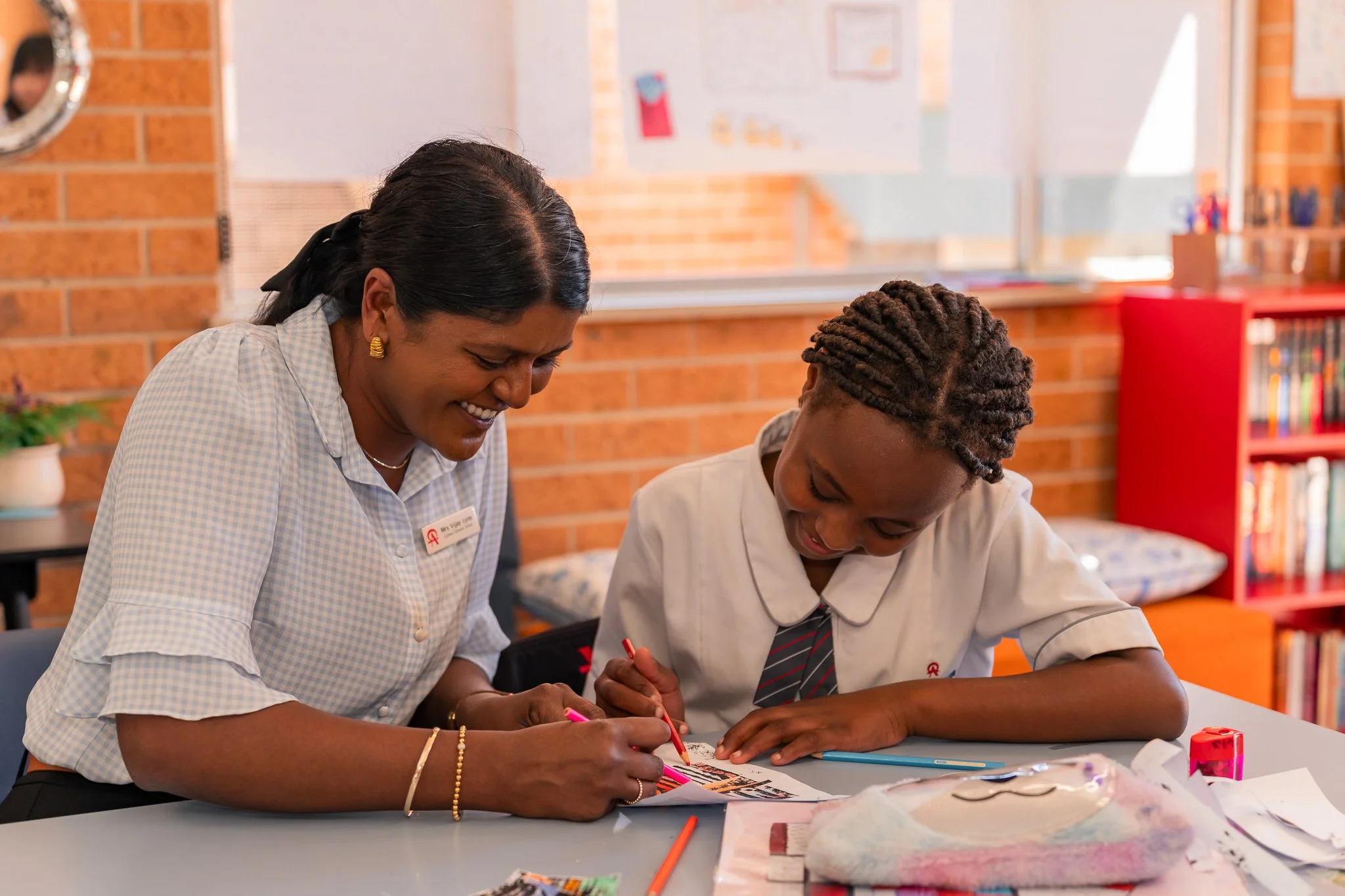 A teacher and a Middle School student smiling at each other while working on a project together in a middle school classroom at Carinya Christian School, Tamworth.