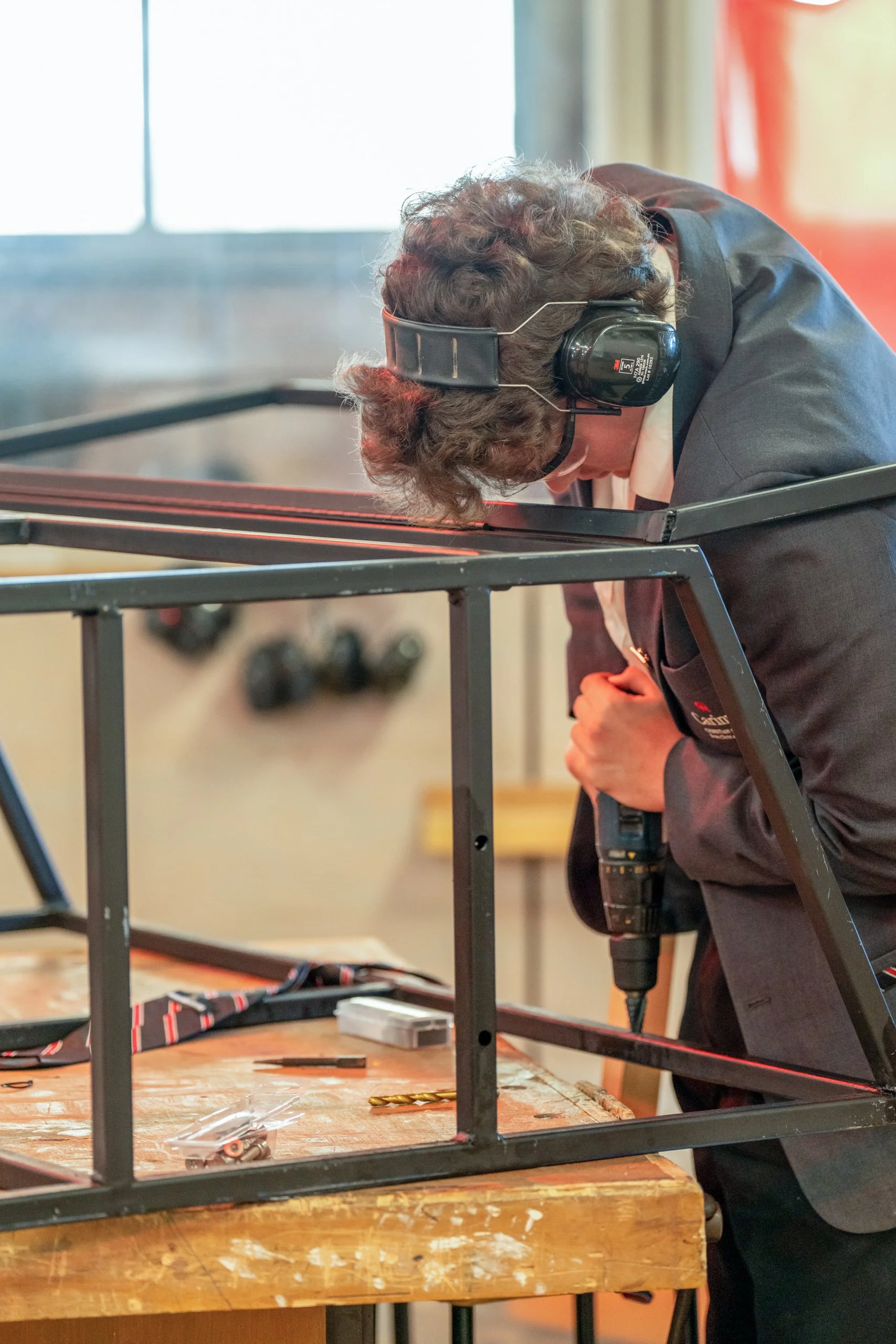 Carinya student a cordless drill on a black metal frame in a Design and Technology classroom at Carinya Christian School, Tamworth.