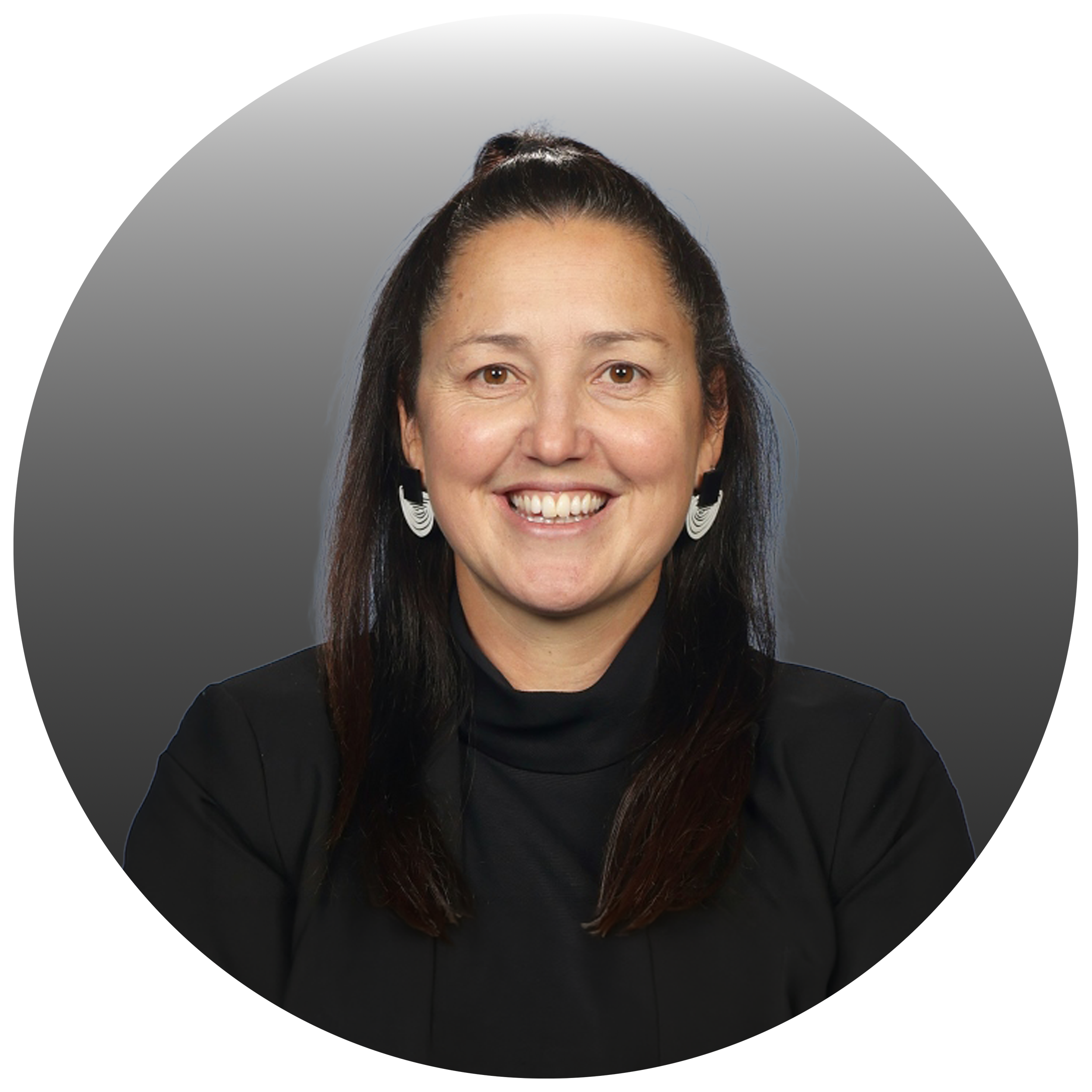 Portrait of a woman with long dark hair, smiling, wearing a black turtleneck and earrings, against a gray background.