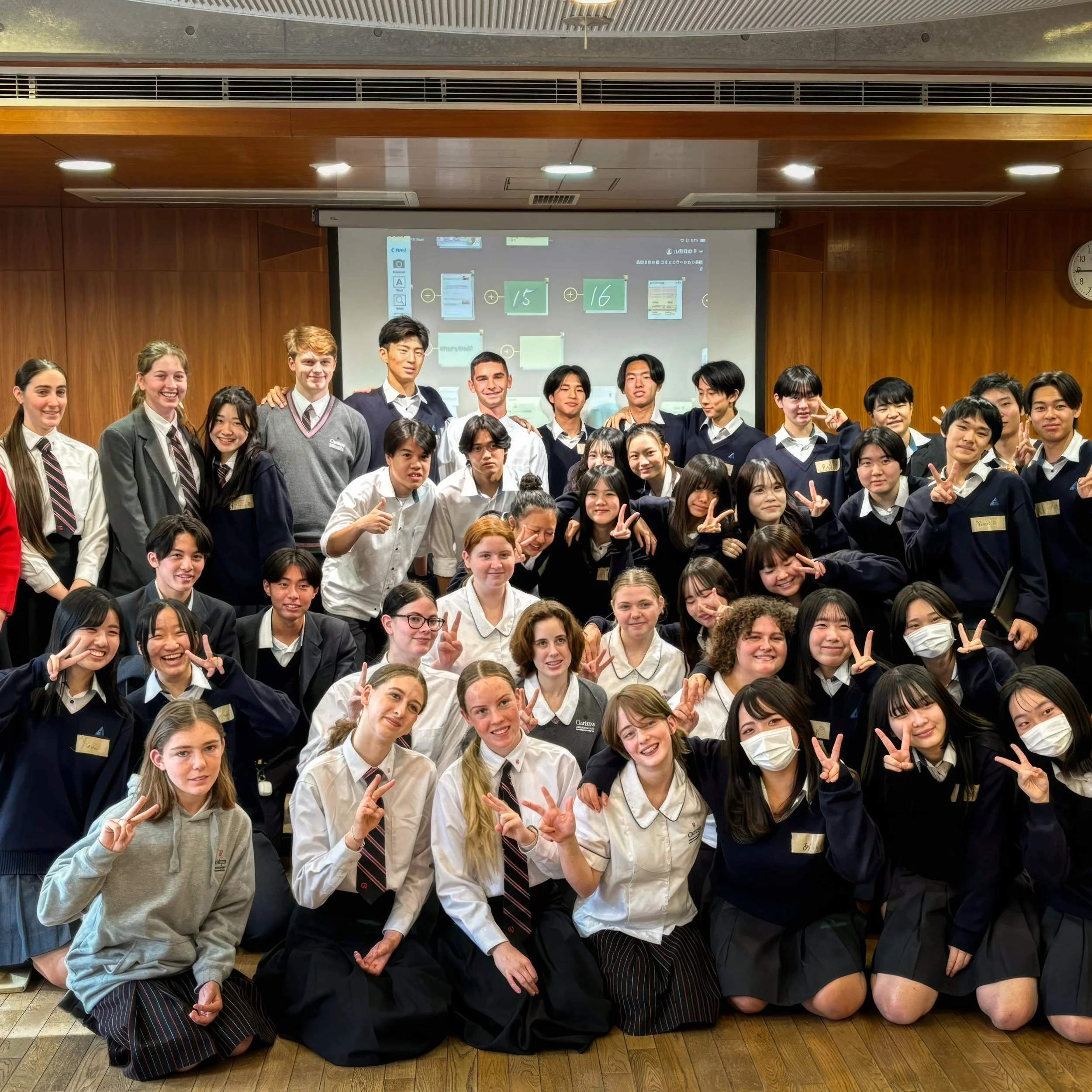 A large group of students in school uniforms posing together in a classroom.