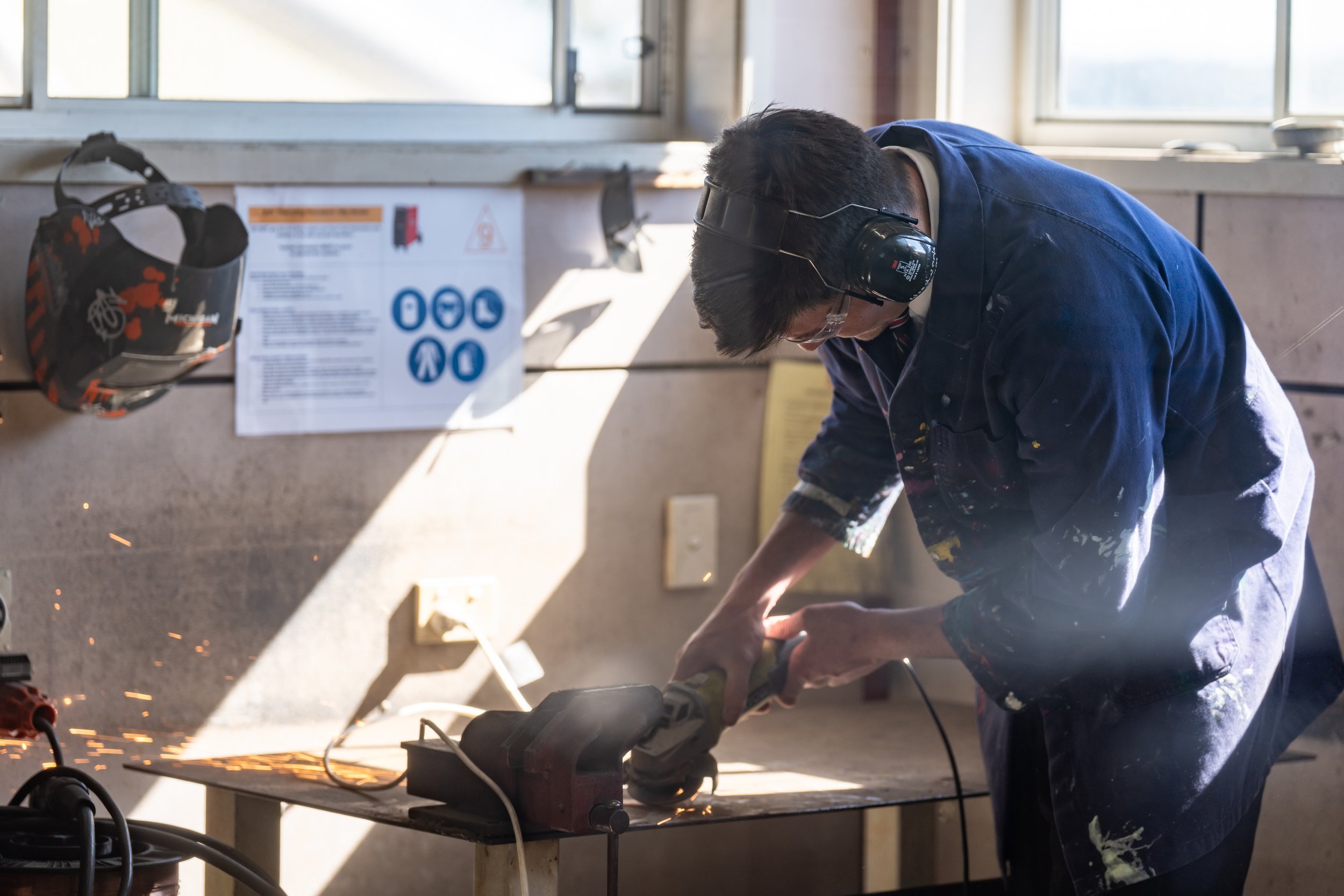 Carinya student cutting metal with a grinder in a Design and Technology classroom at Carinya Christian School, Tamworth