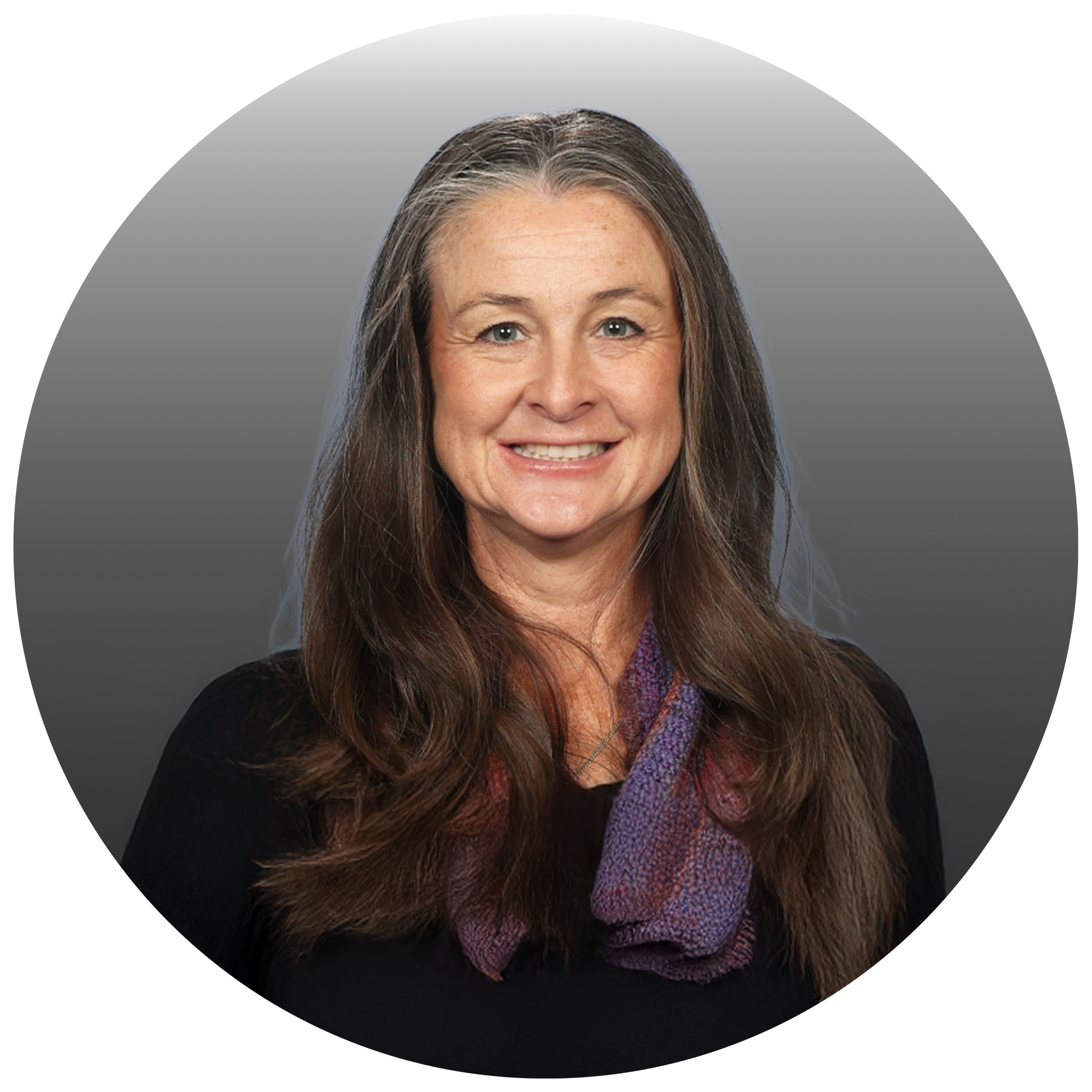 A middle-aged woman with long brown hair, smiling, wearing a black top and a purple scarf, posed against a neutral gray background.