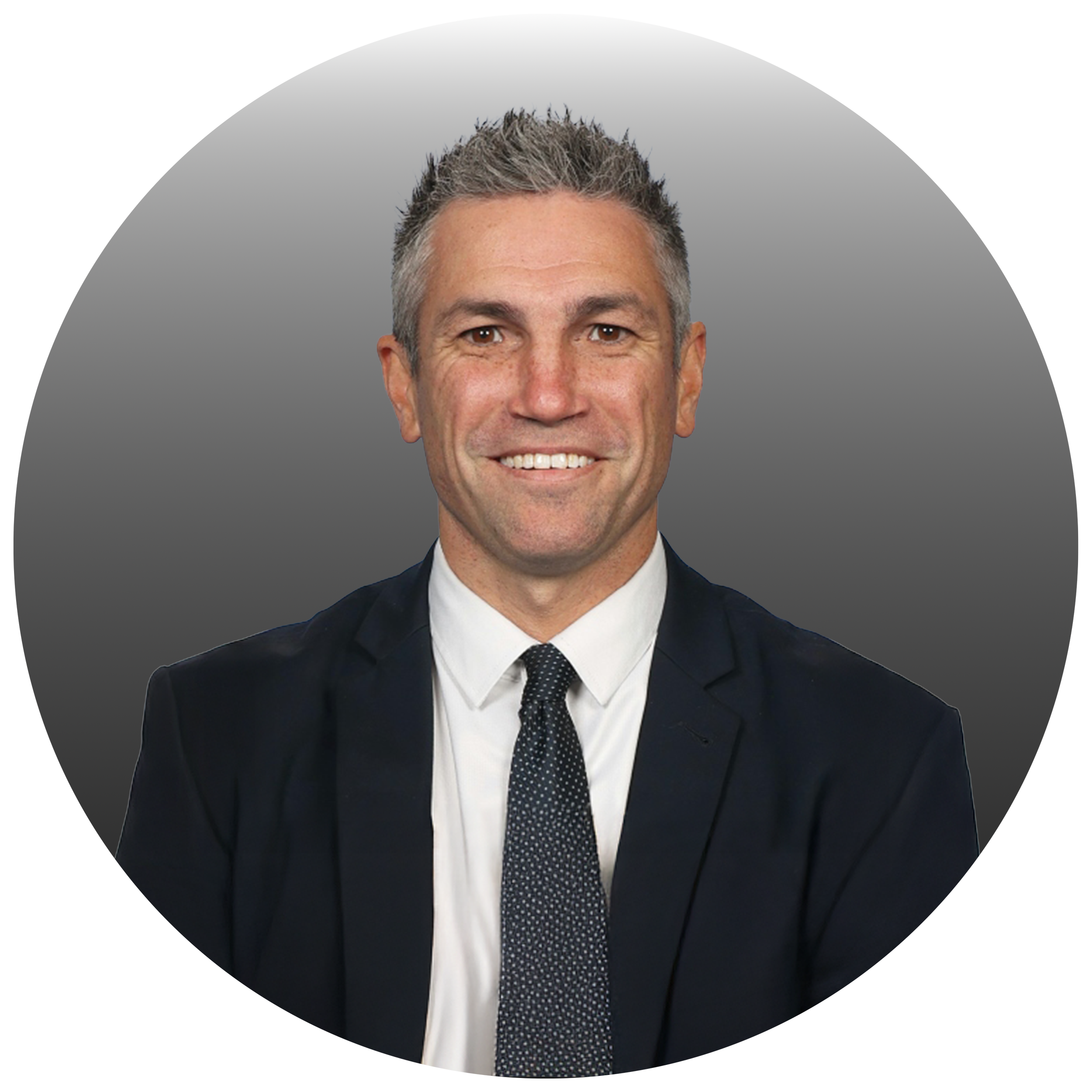 Professional headshot of a smiling man wearing a dark suit, white shirt, and a patterned tie.