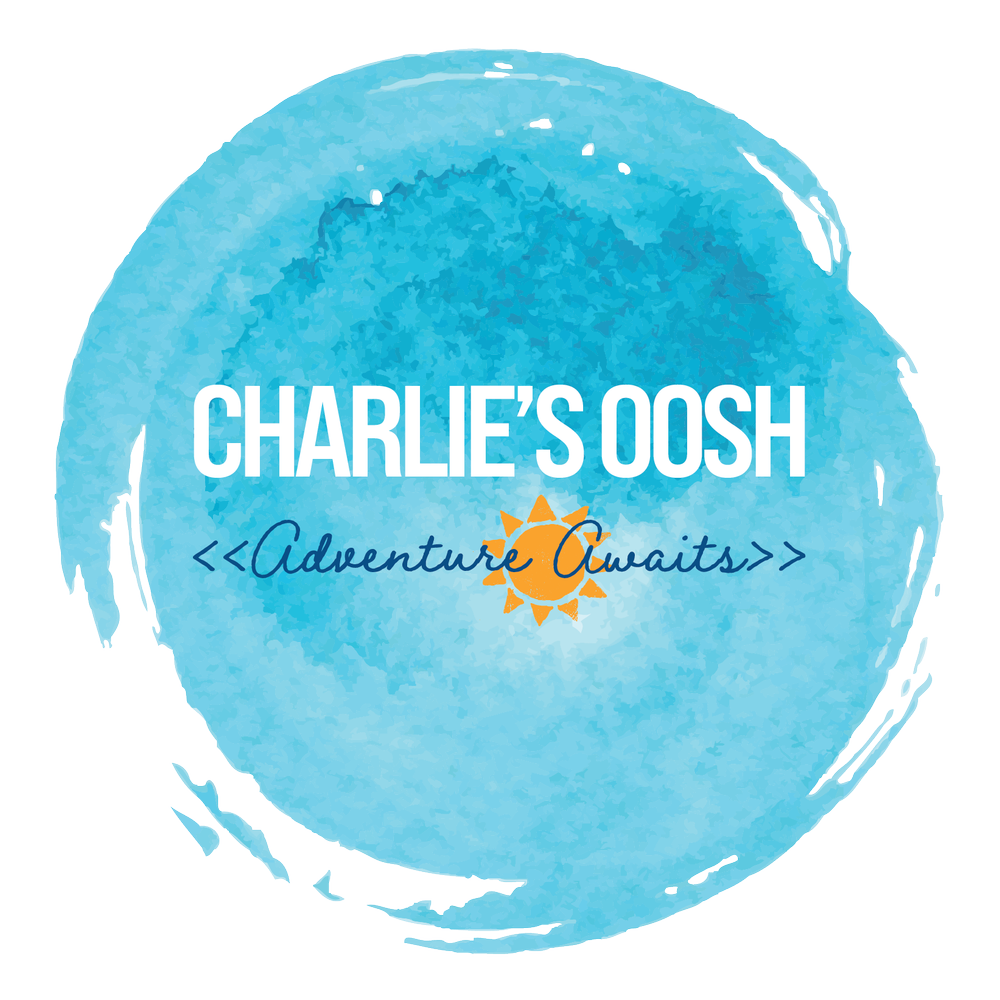 A blue watercolor-style logo with the text "Charlie's Oosh" and a small orange sun illustration, accompanied by the phrase "Adventure Awaits" in cursive.