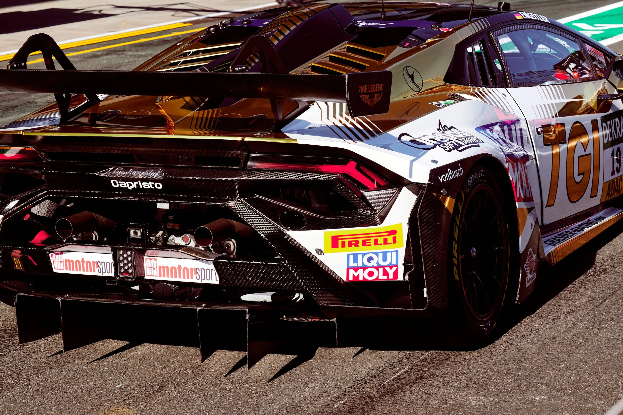 A race car on a track with sponsorship logos including Pirelli, Liqui Moly, and Auto Bild motorsport, featuring a prominent rear wing and aerodynamic design.