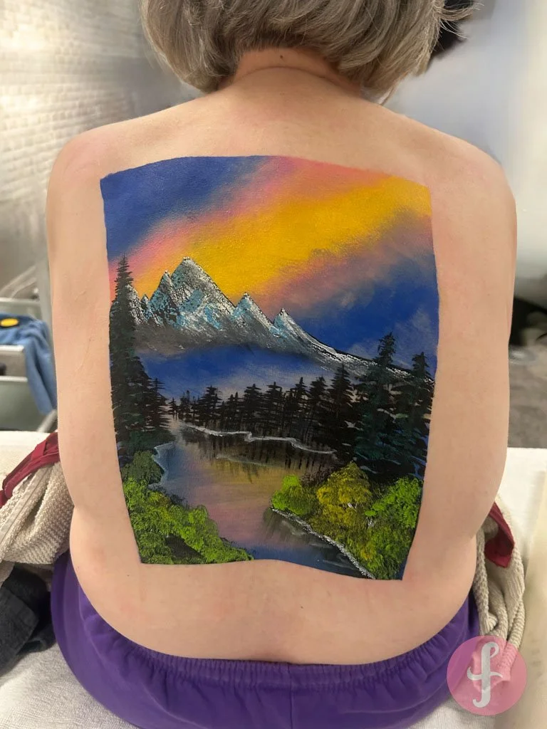 Voor deze klastaak bracht ik een Bob Ross-landschap tot leven op de rug. Een creatieve uitdaging waarin schilderkunst en bodypaint samenkwamen. 🌲🎨