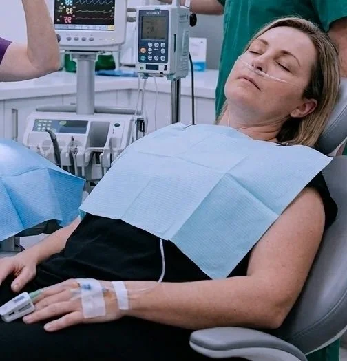 A woman lying in a dental chair, comfortable and relaxed while having IV twilight sedation.