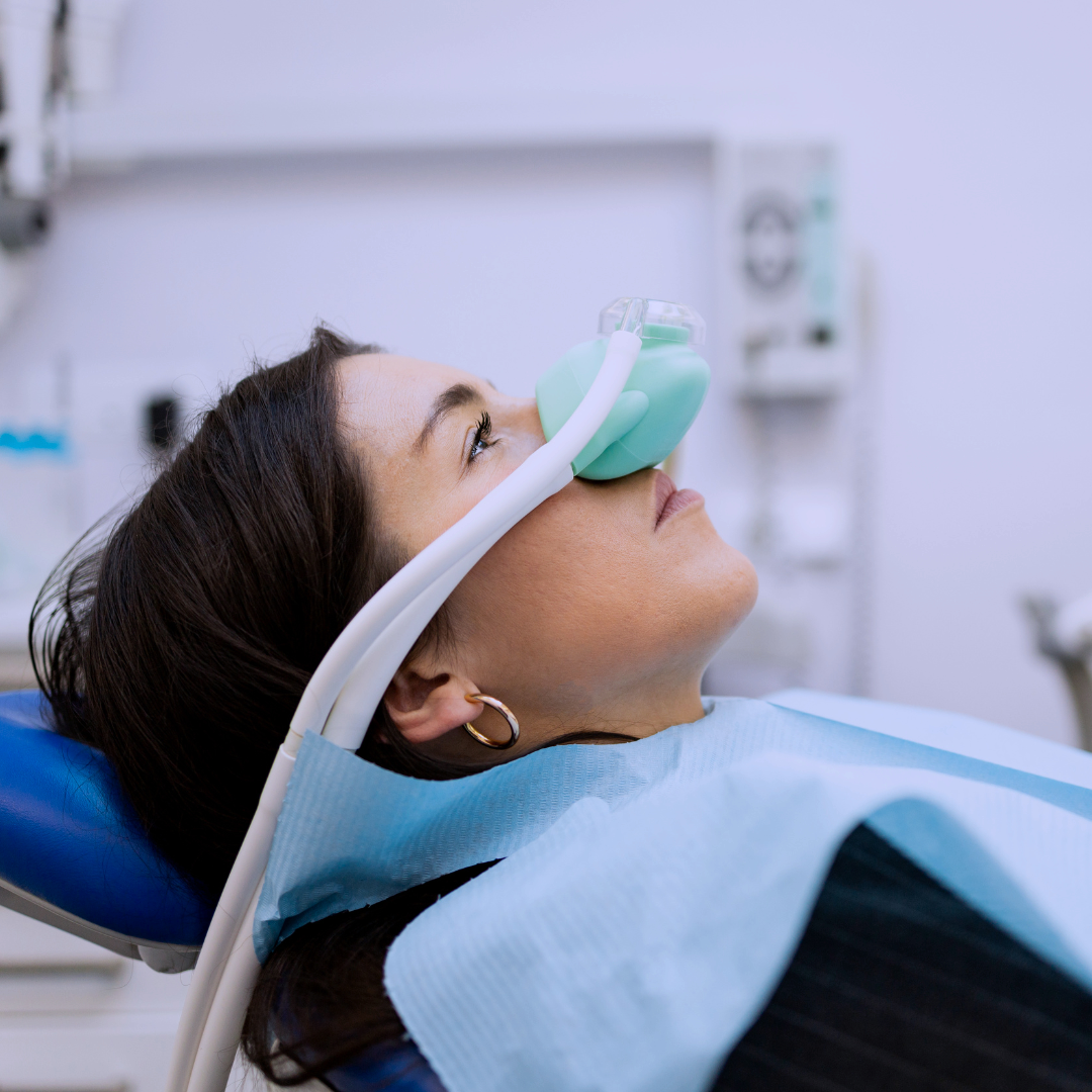 Woman lying in dental chair using inhalation happy gas mask